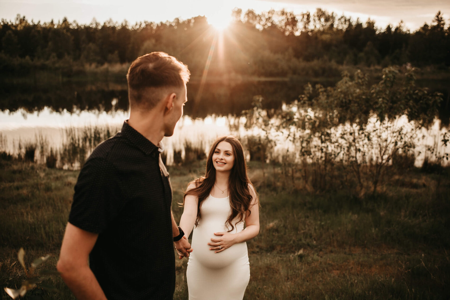 Husband holding his wife's hand, looking lovingly at her during maternity photo shoot