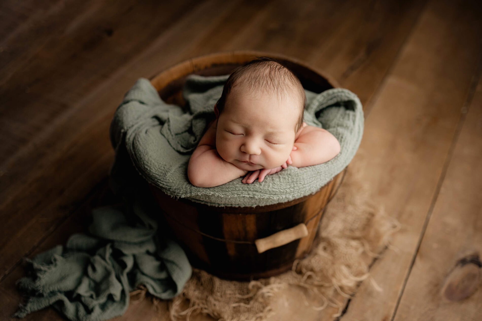 Baby boy posed in a bucket during newborn photo shoot in Seattle studio