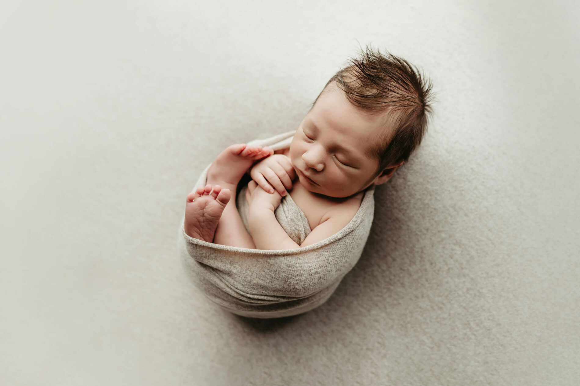 Newborn photography posing sample, sleeping baby boy wrapped in blankets