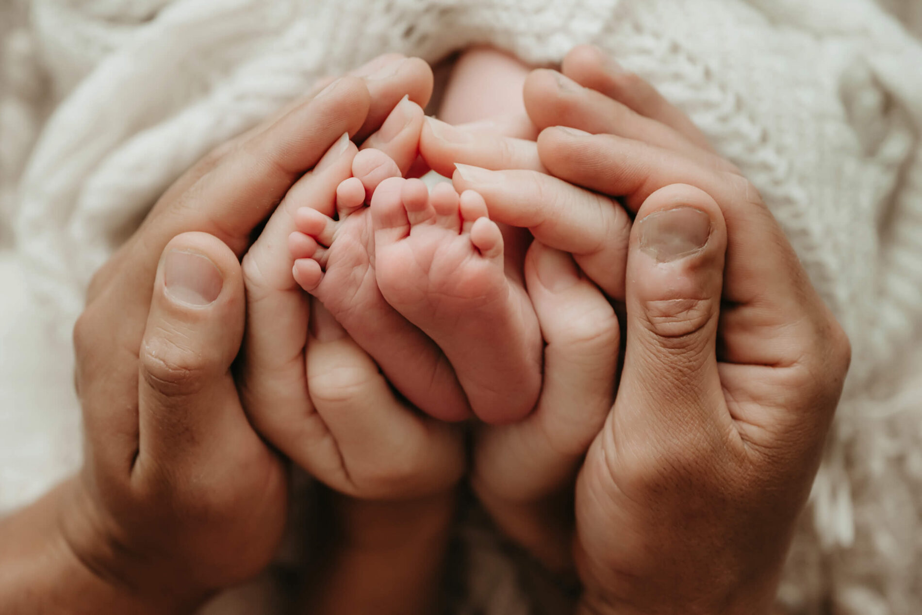 Newborn photo idea, parent's hands wrapped around baby's feet
