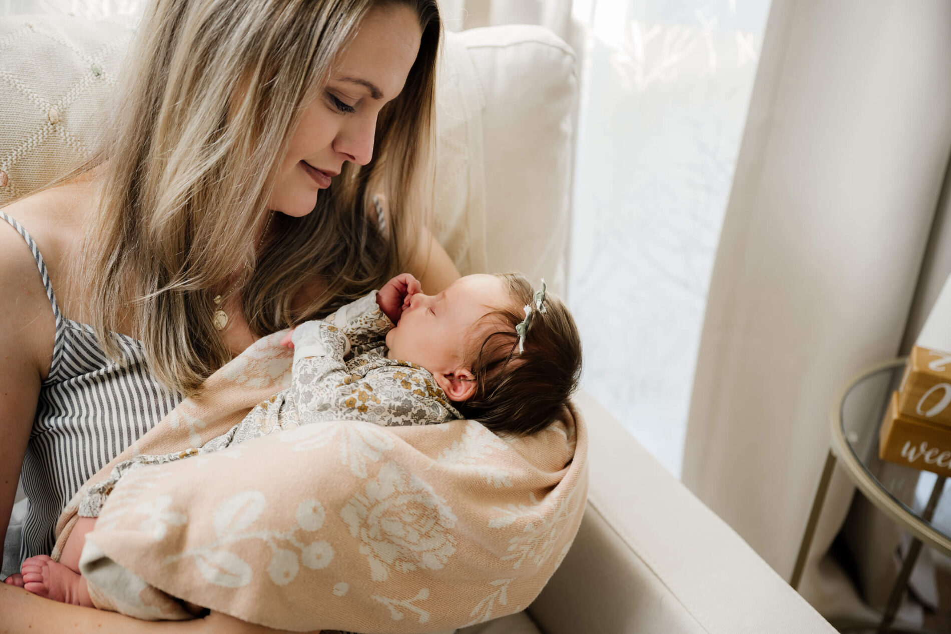 Seattle in-home newborn photography, mom holding her daughter in her arms in a rocking chair in a nursery