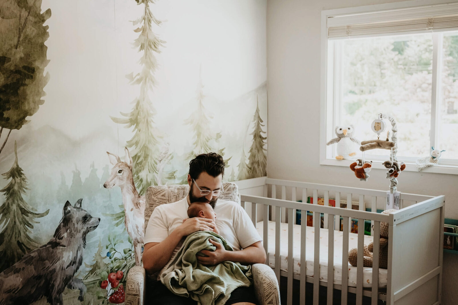 A photo from an in-home newborn photo shoot, dad cuddling with his baby in a nursery