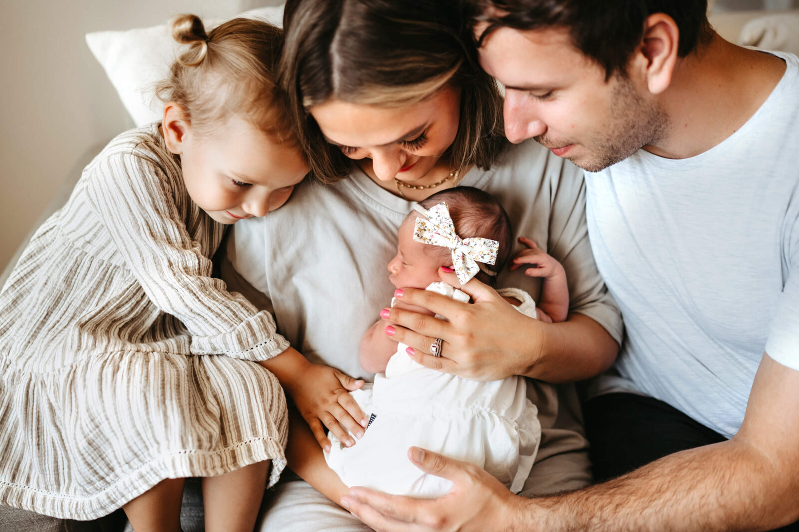 A family cuddling with their newborn baby girl, a photo from in-home photo session