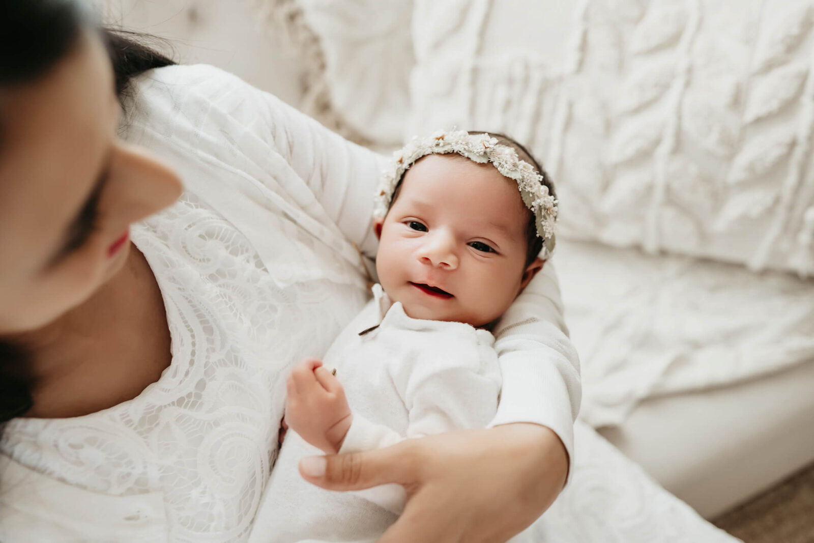 Mom in soft focus holding her newborn daughter during a photo shoot