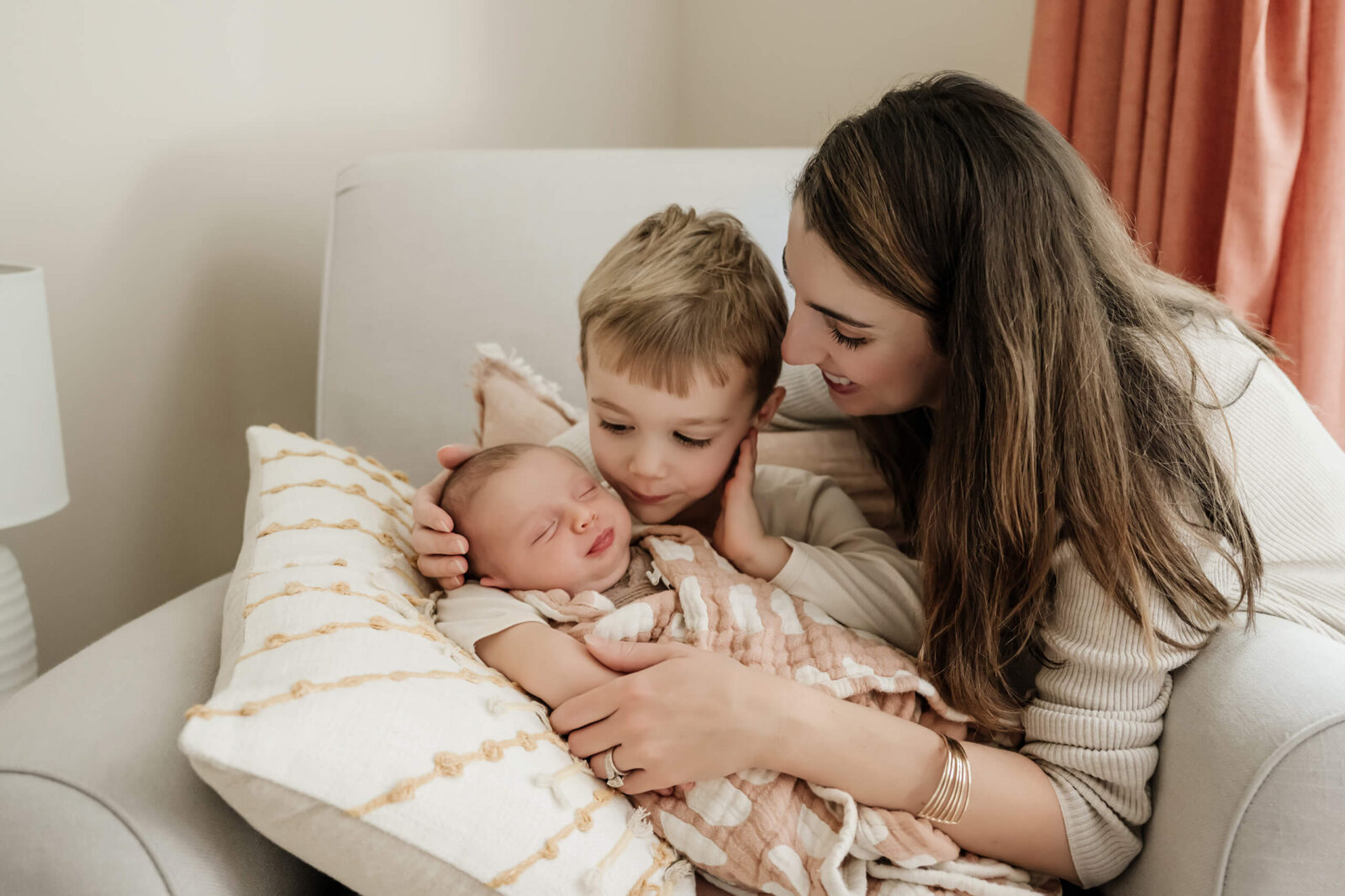 In-home newborn photo shoot, mom, older brother, and baby hugging