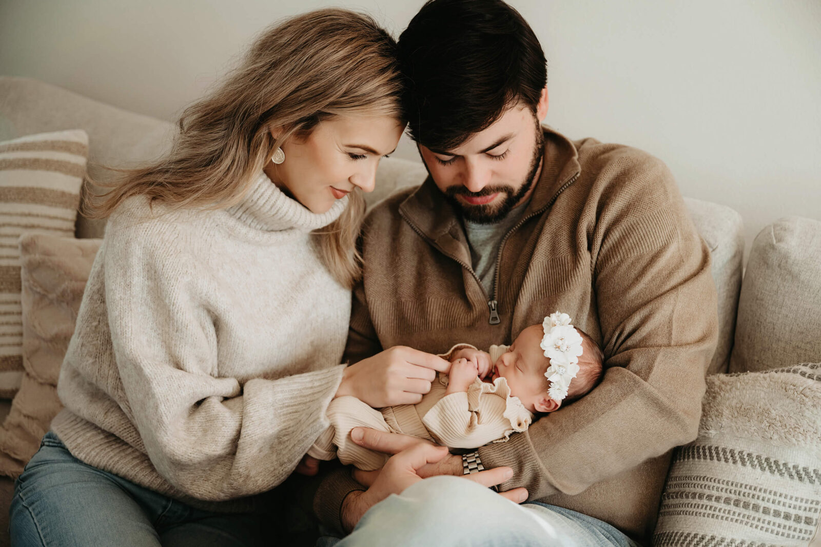 Parents holding their newborn on the couch during a relaxed in-home newborn photo session