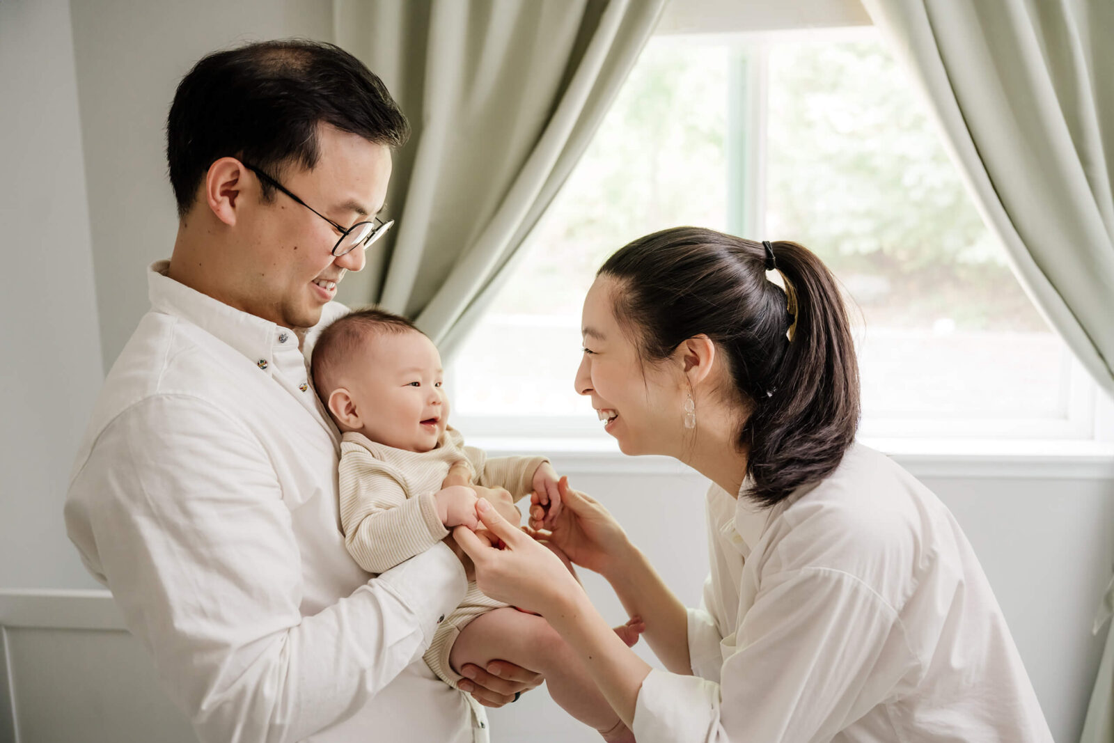 Parents laughing with their 3-month-old baby during a relaxed in-home newborn photo session