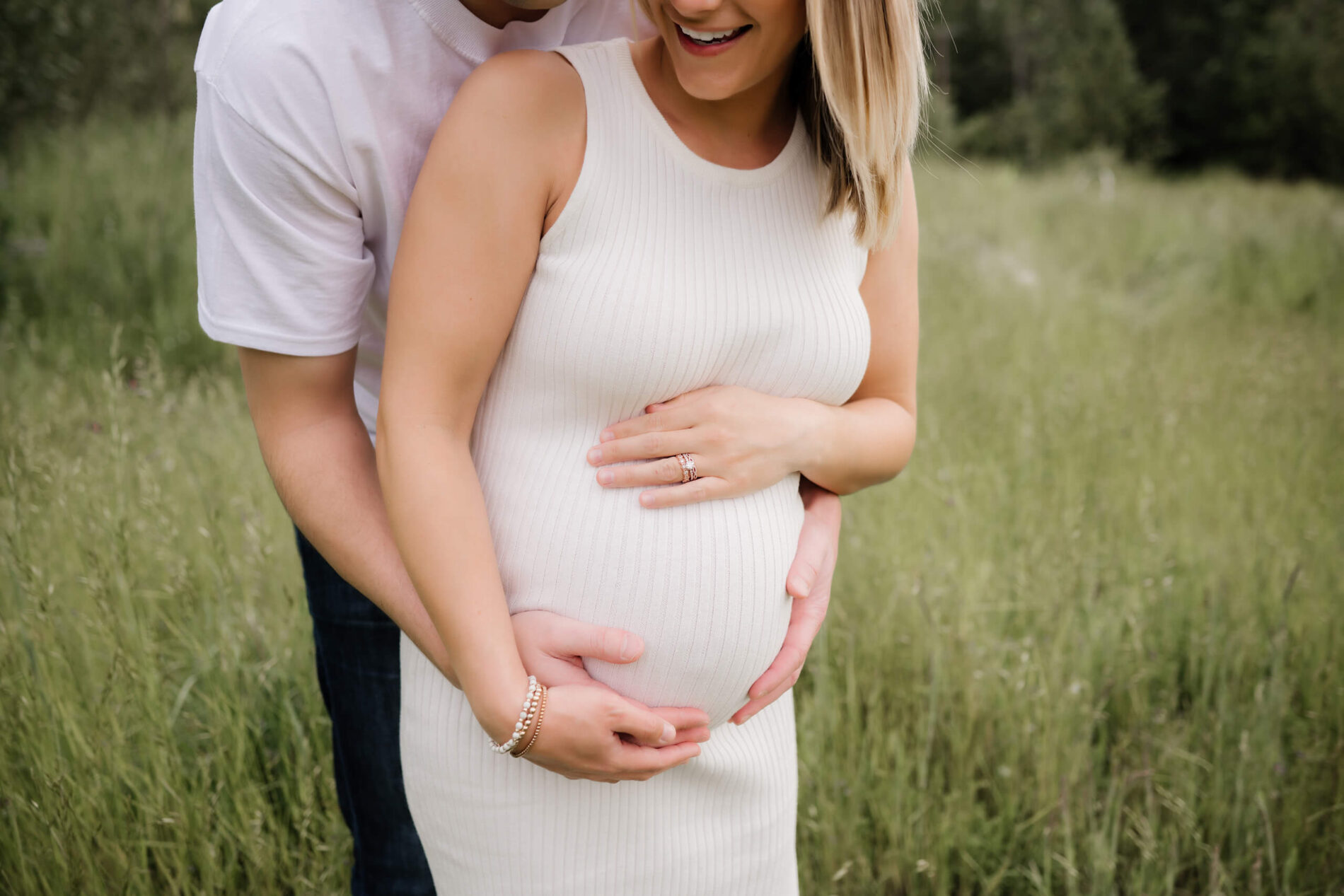Bellevue pregnancy photo shoot, husband hugging his pregnant wife from behind in a field