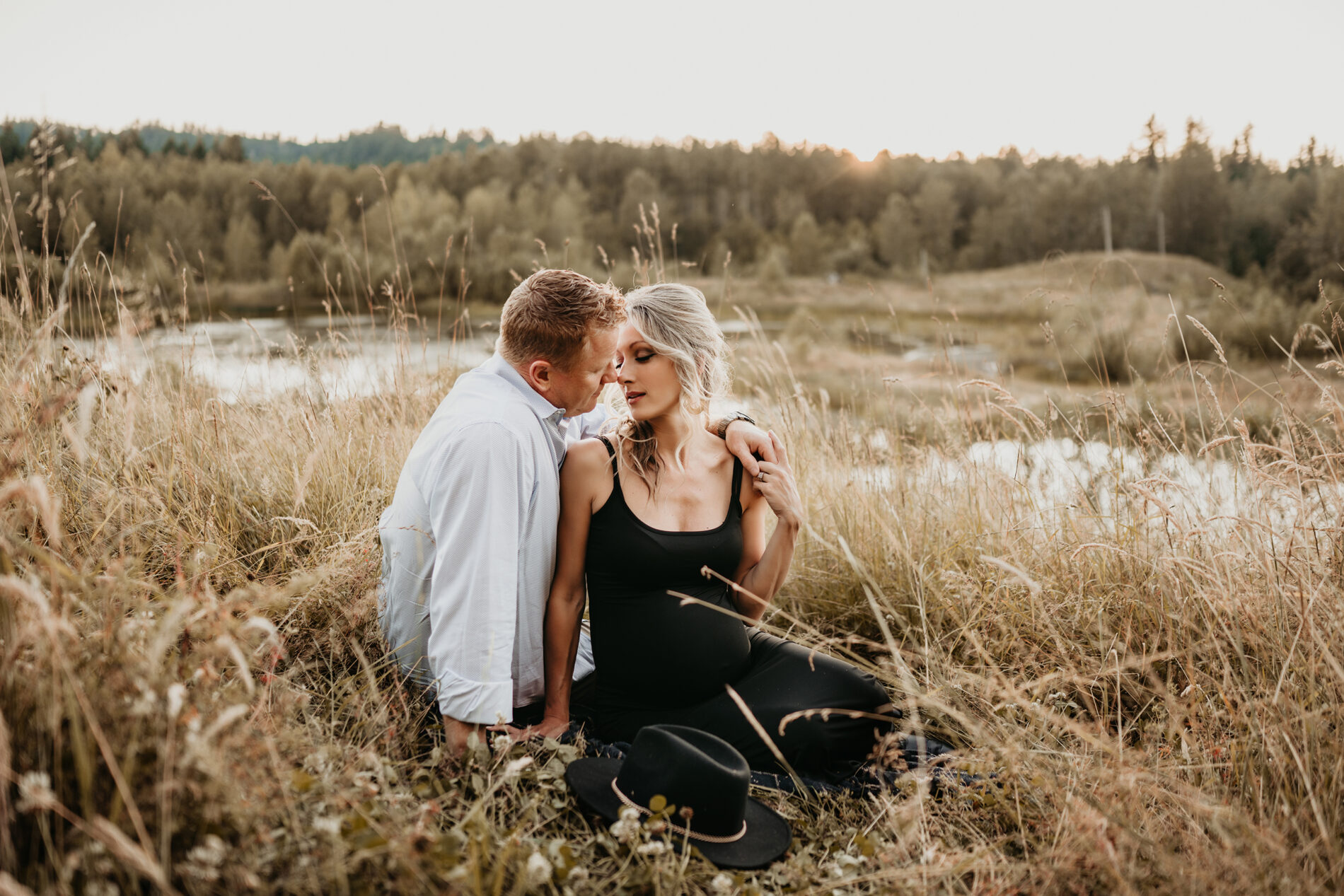 Couples maternity photo shoot in Bellevue, husband and wife sitting in a field of tall grass
