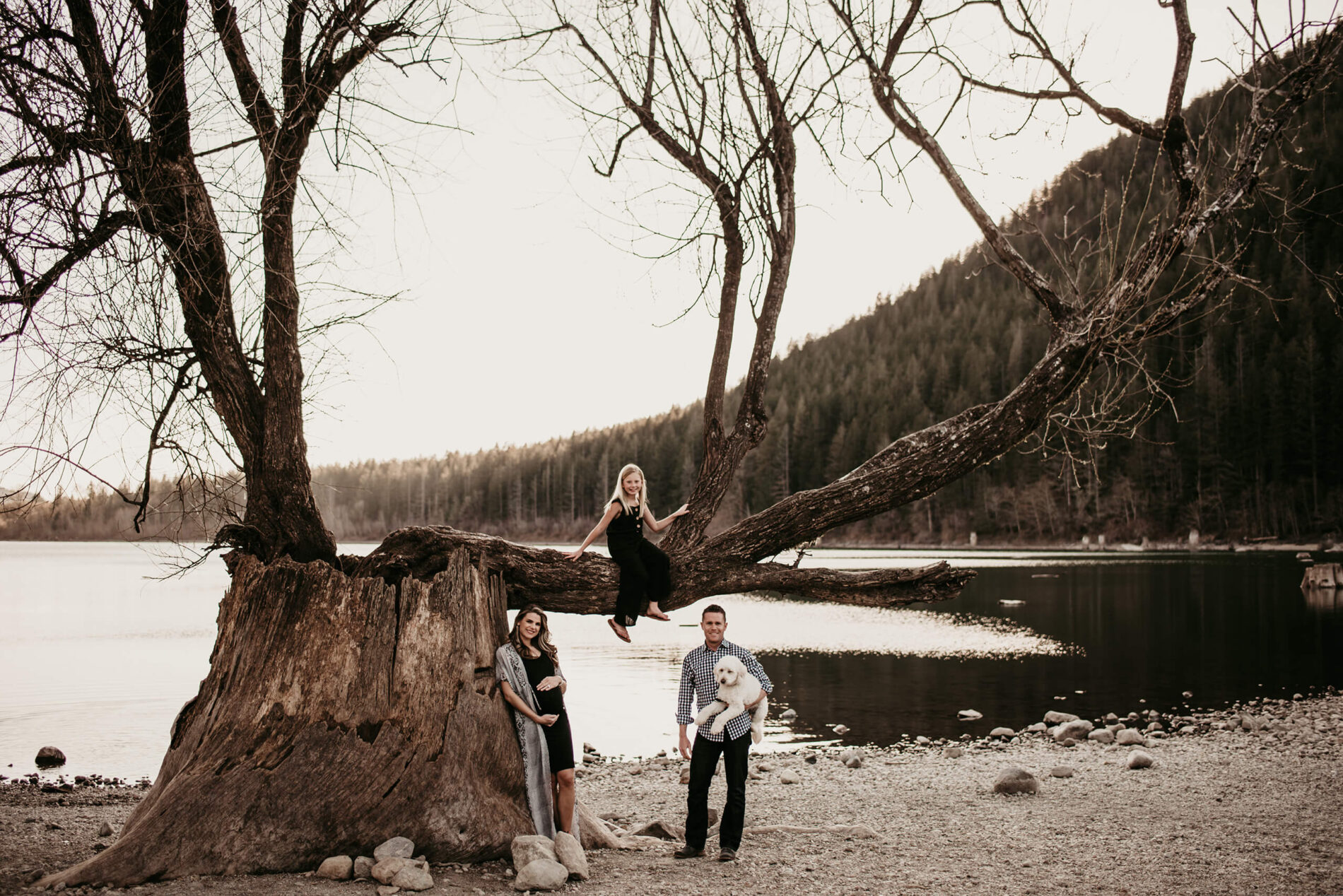 A family posed on a beach of a lake during maternity photo shoot in Seattle