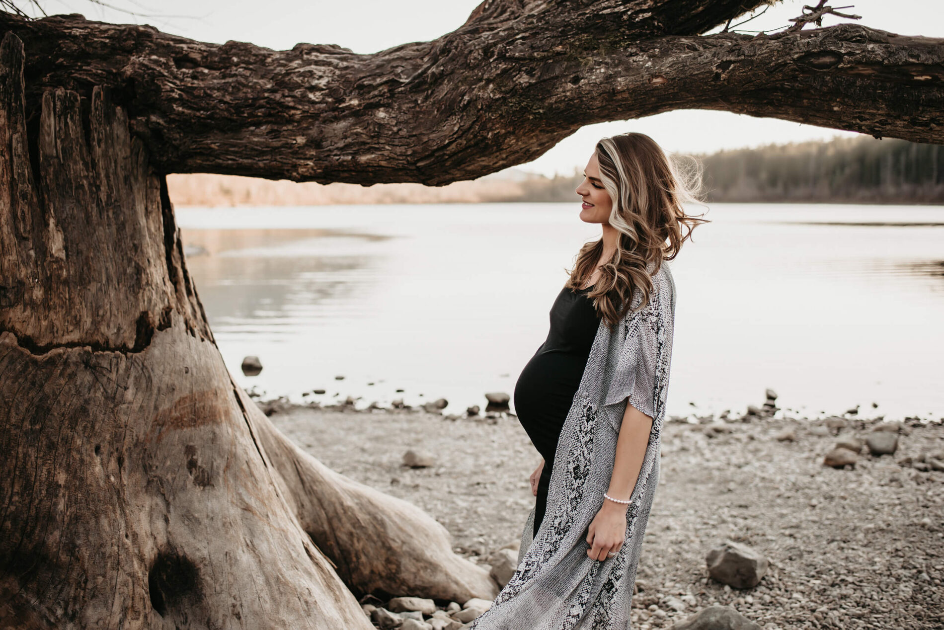 A pregnant woman posing during a maternity photo shoot in Seattle, lake in the background