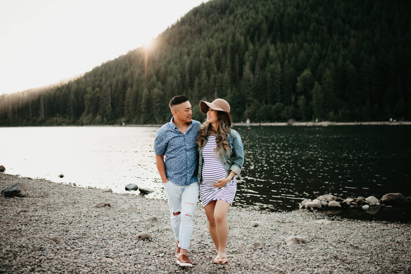 A pregnant couple walking on a beach during maternity photo shoot in Seattle, mountain in the background