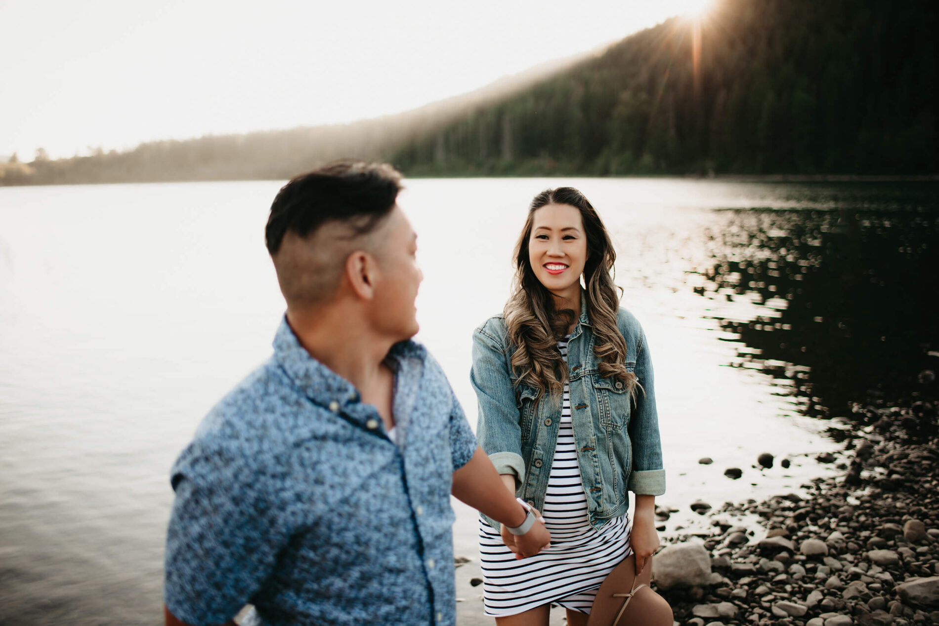 A young couple holding hands during a maternity photo shoot in Seattle, lake and mountains in the background