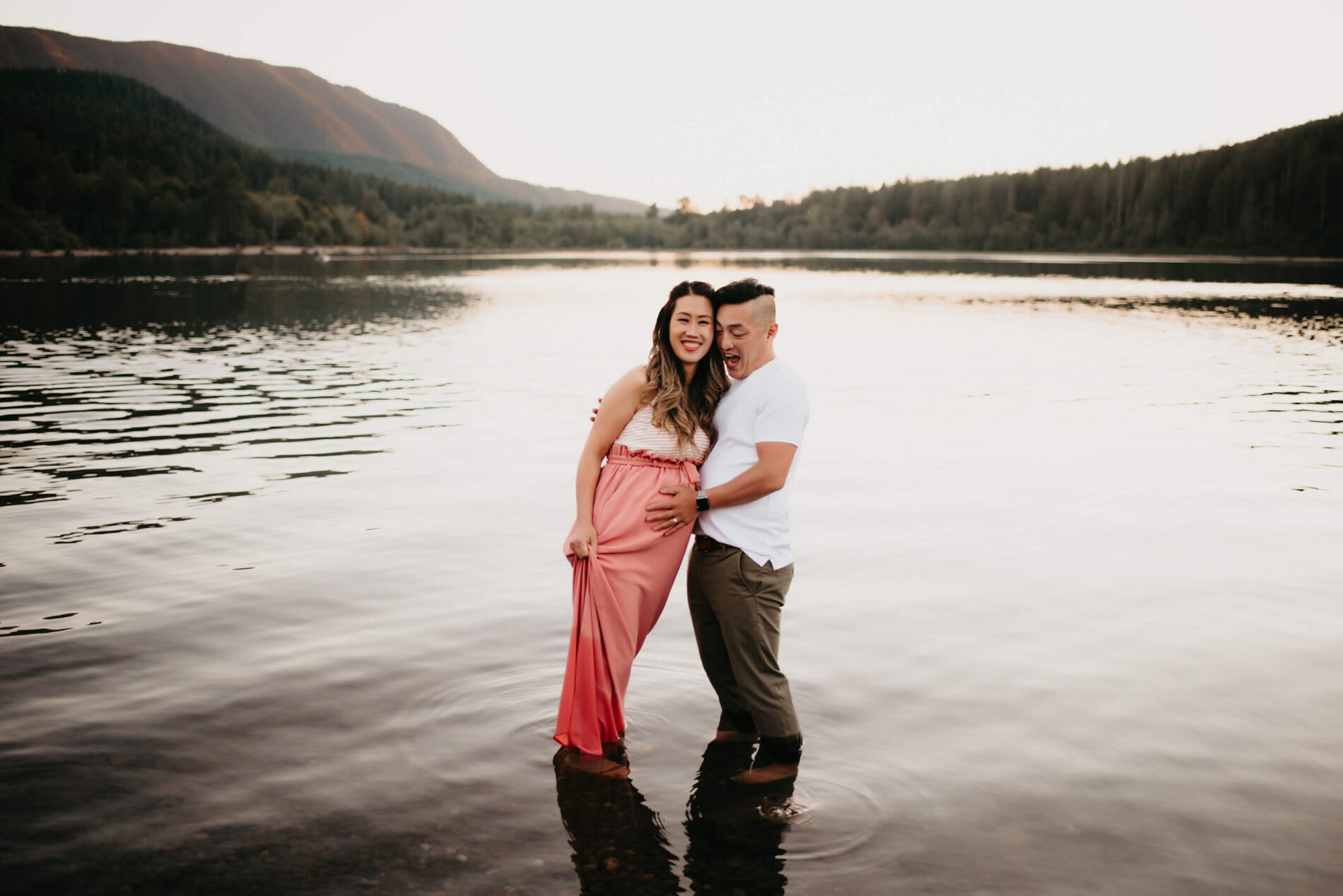 A couple standing in a lake during maternity photo shoot in Seattle, mountains in the background