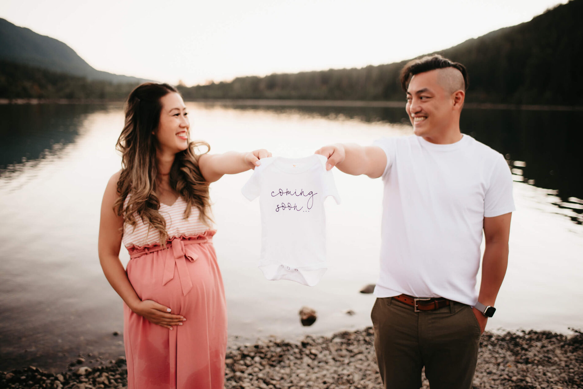 A young happy couple holding a onesie during a maternity photo shoot in Seattle