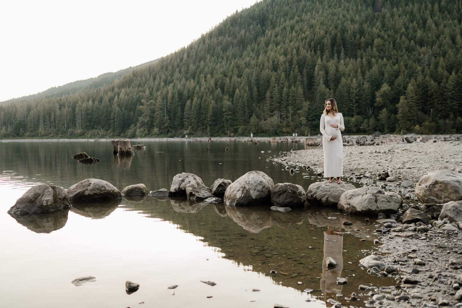A pregnant woman naturally posing during a photo shoot in Seattle, mountains and lake in the background