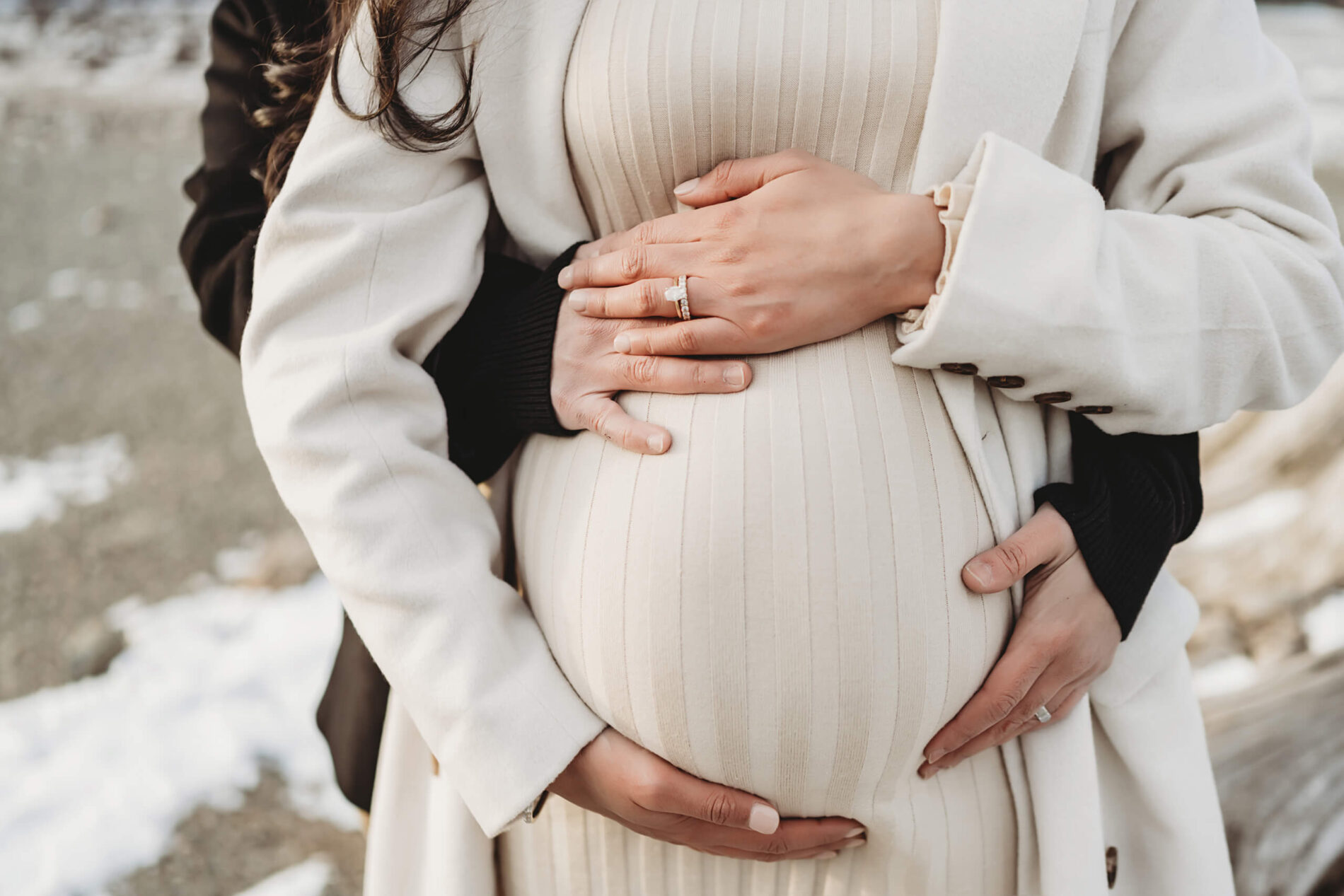 Pregnancy photo shoot, husband and wife wrapping their hands around the stomach