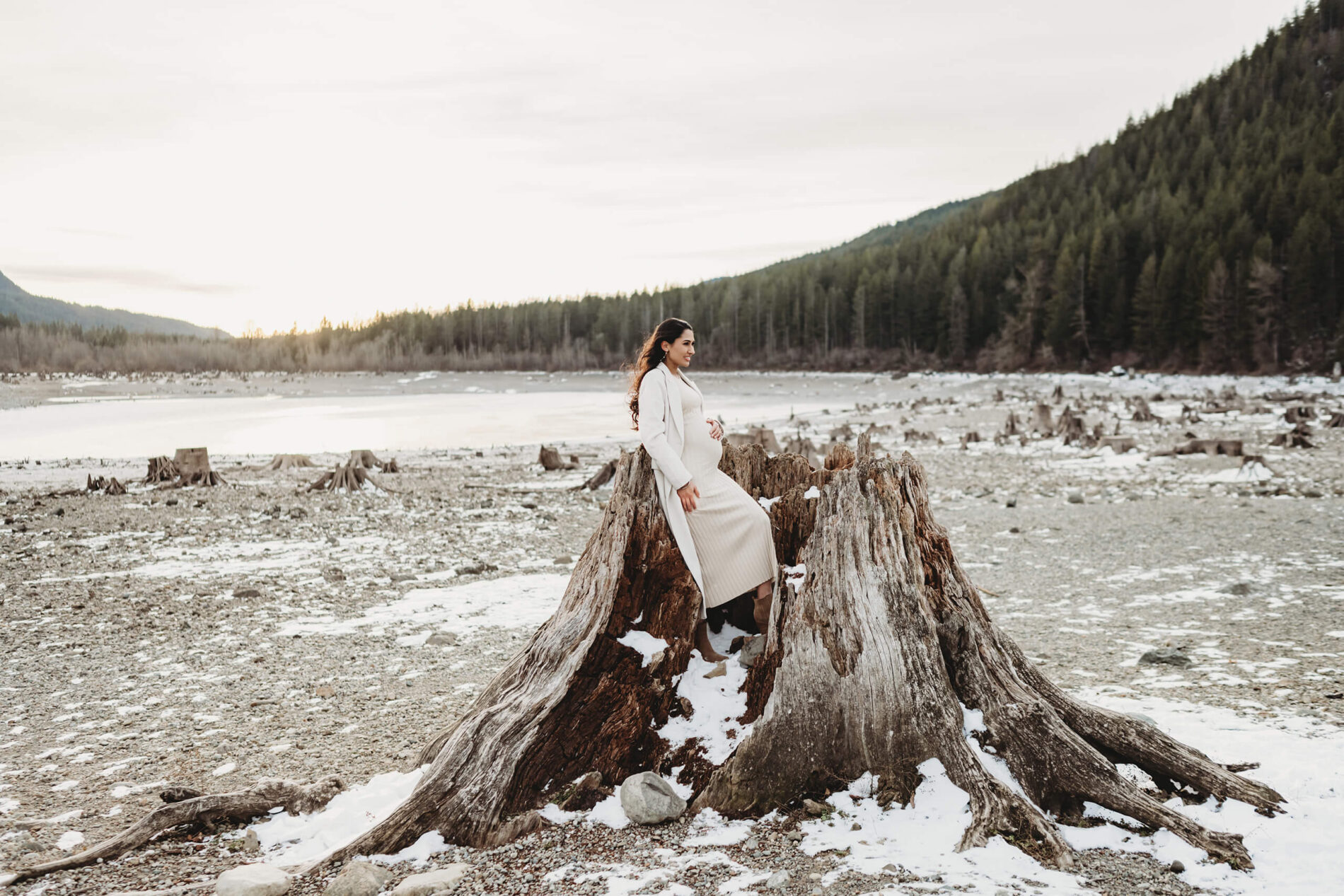 A young pregnant woman naturally posed during a photo shoot in Seattle with mountains and lake in the background