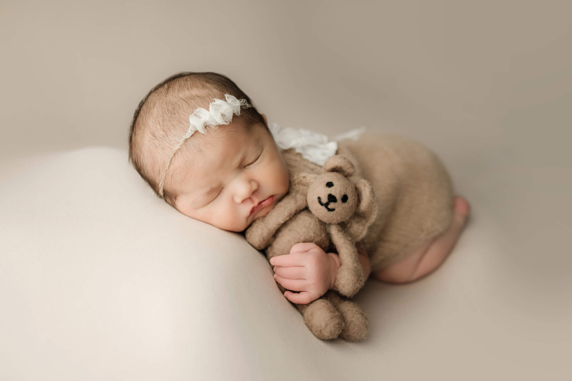 Kirkland studio newborn photography. Sleeping newborn girl beautifully posed, holding a stuffed bear.