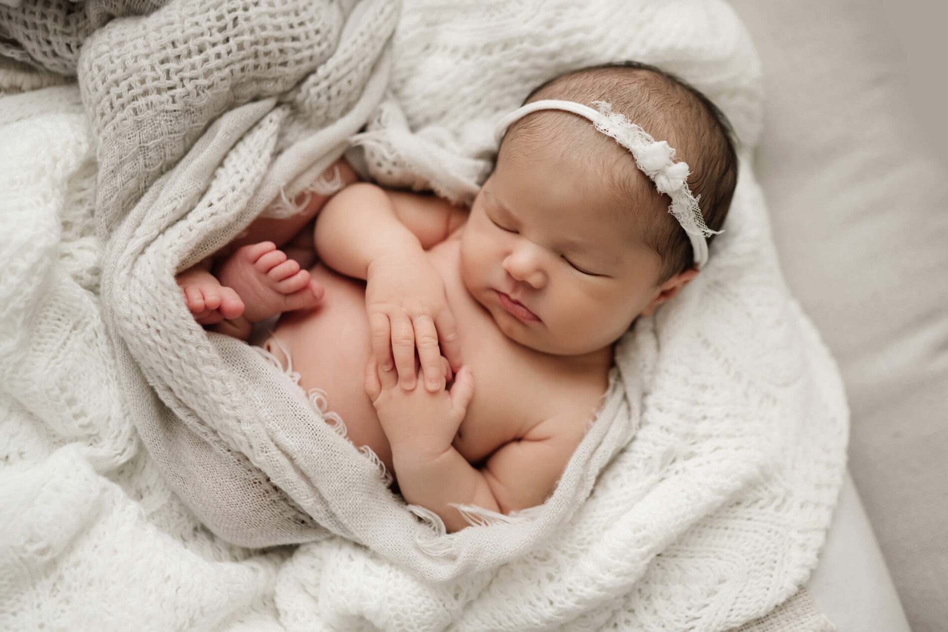 Posed newborn photo. Sleeping baby girl wearing a headband.