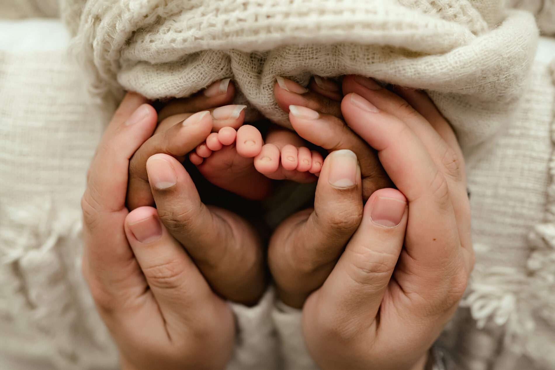 Unique newborn photo. Mom and dad's hands wrapped around baby's tiny fee.