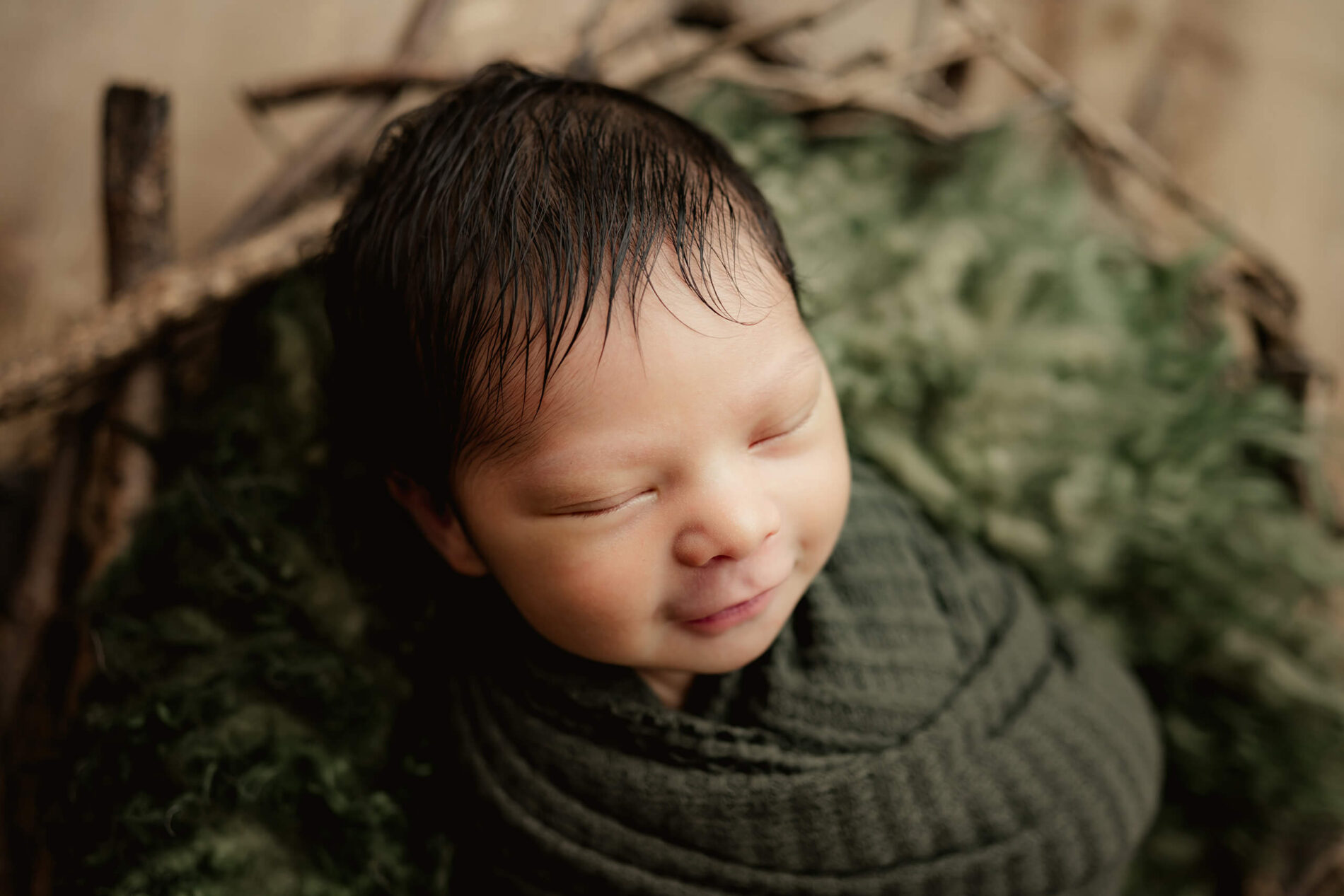 Seattle area newborn photography. Posed portrait of infant boy smiling in his sleep during a photo shoot.