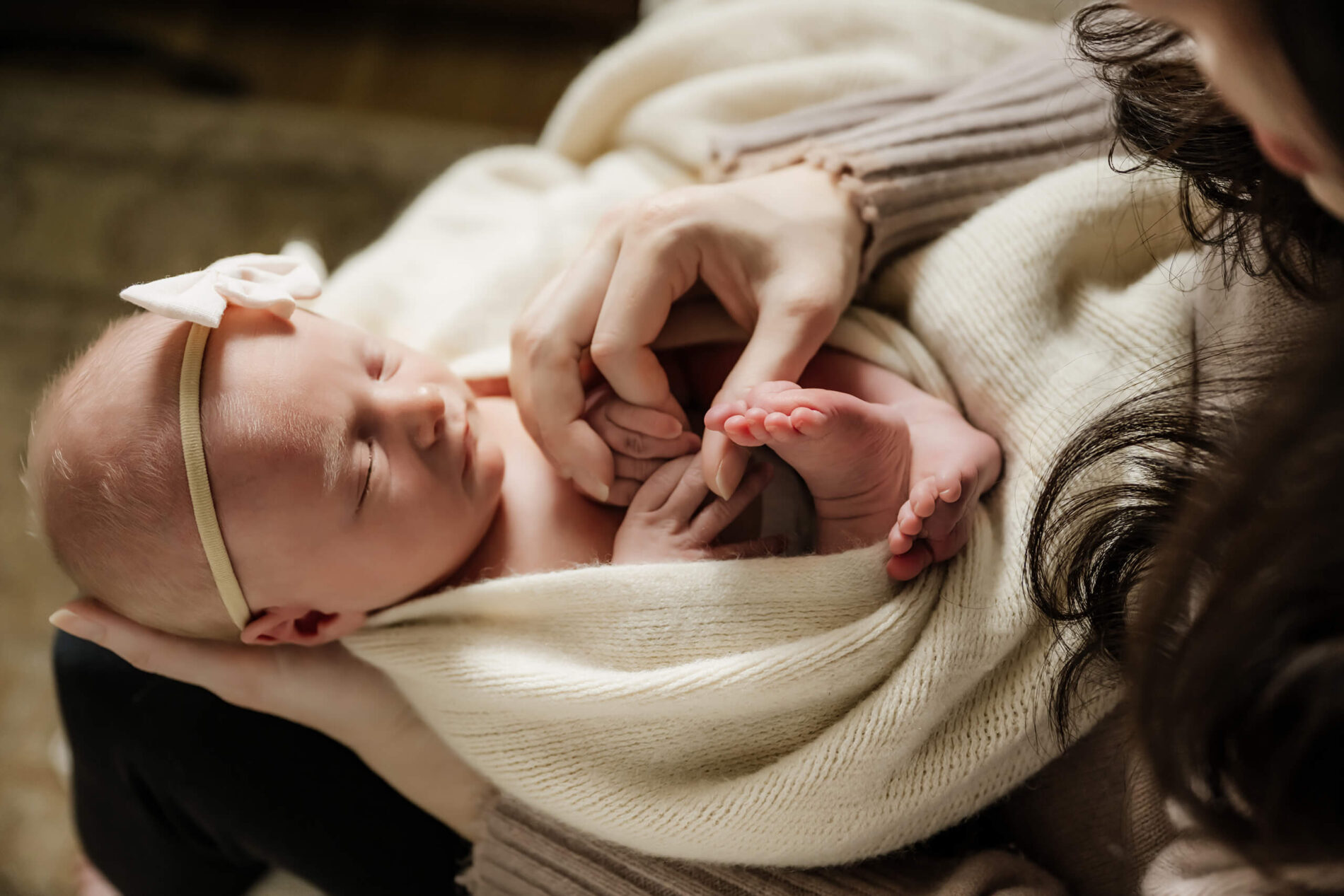 In home newborn photo shoot. Portrait of mom cuddling with her infant daughter.