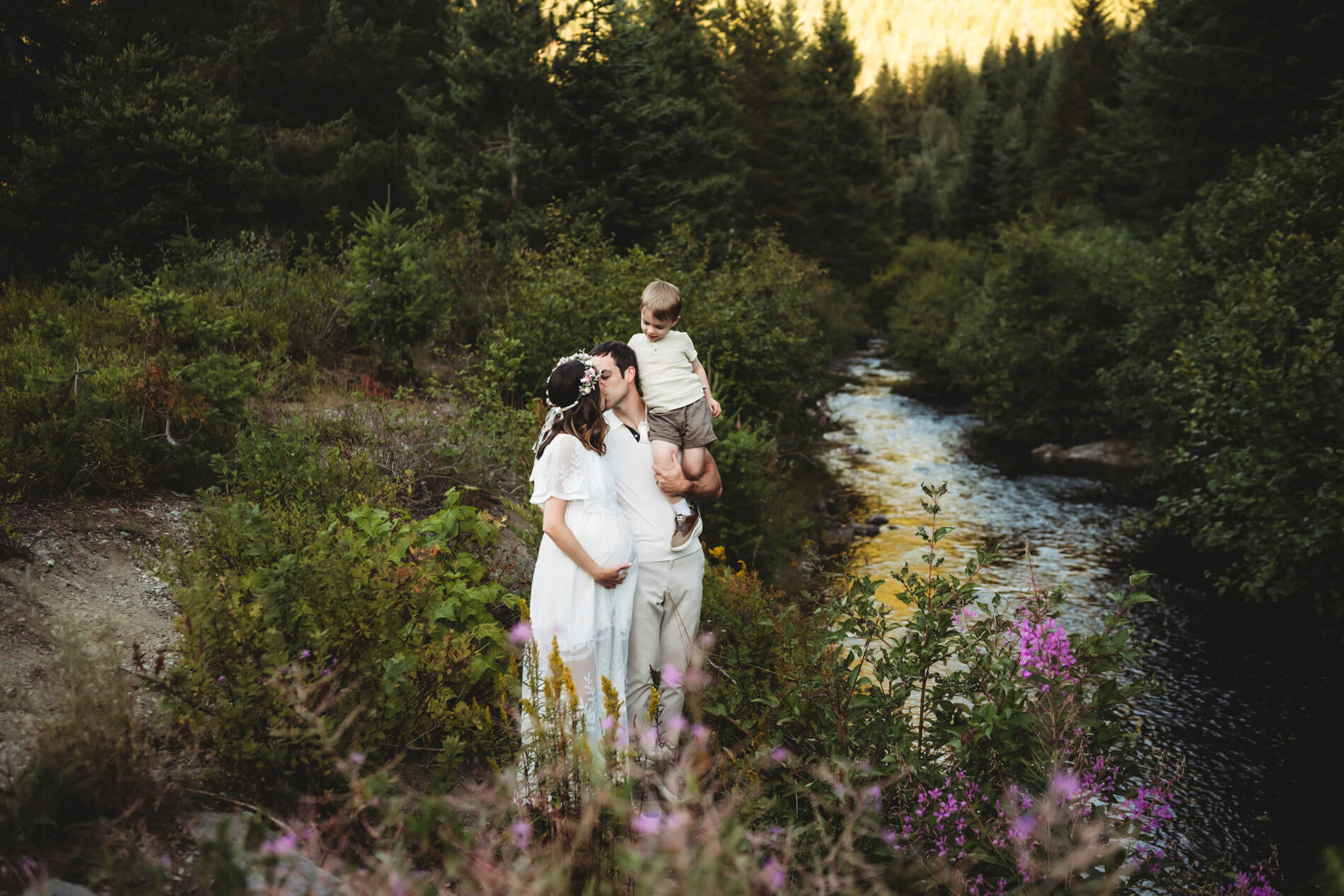 Pregnant woman in a white dress with her family posed next to a river during a photoshoot in Seattle
