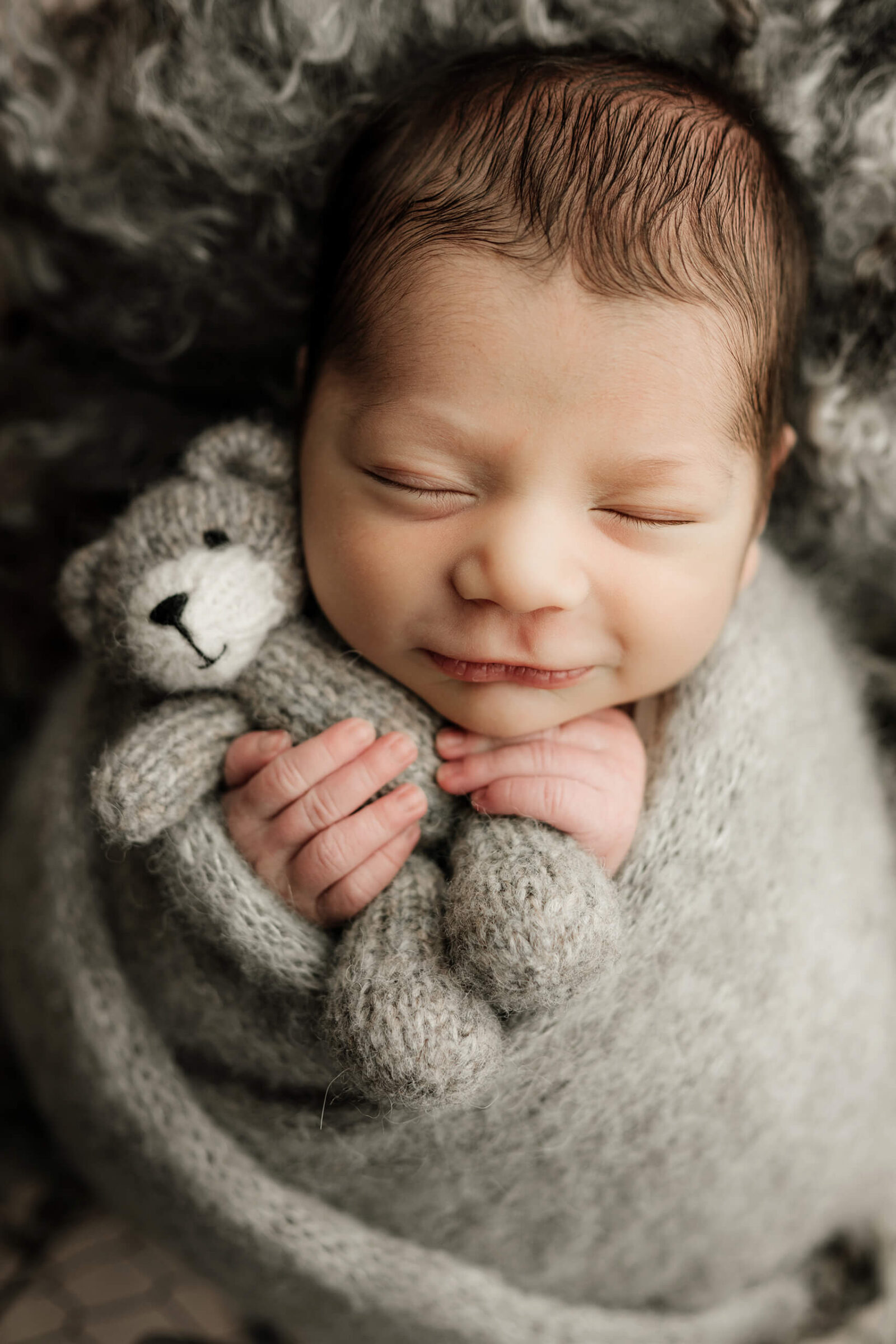 Sleeping newborn boy smiling during a studio portrait.