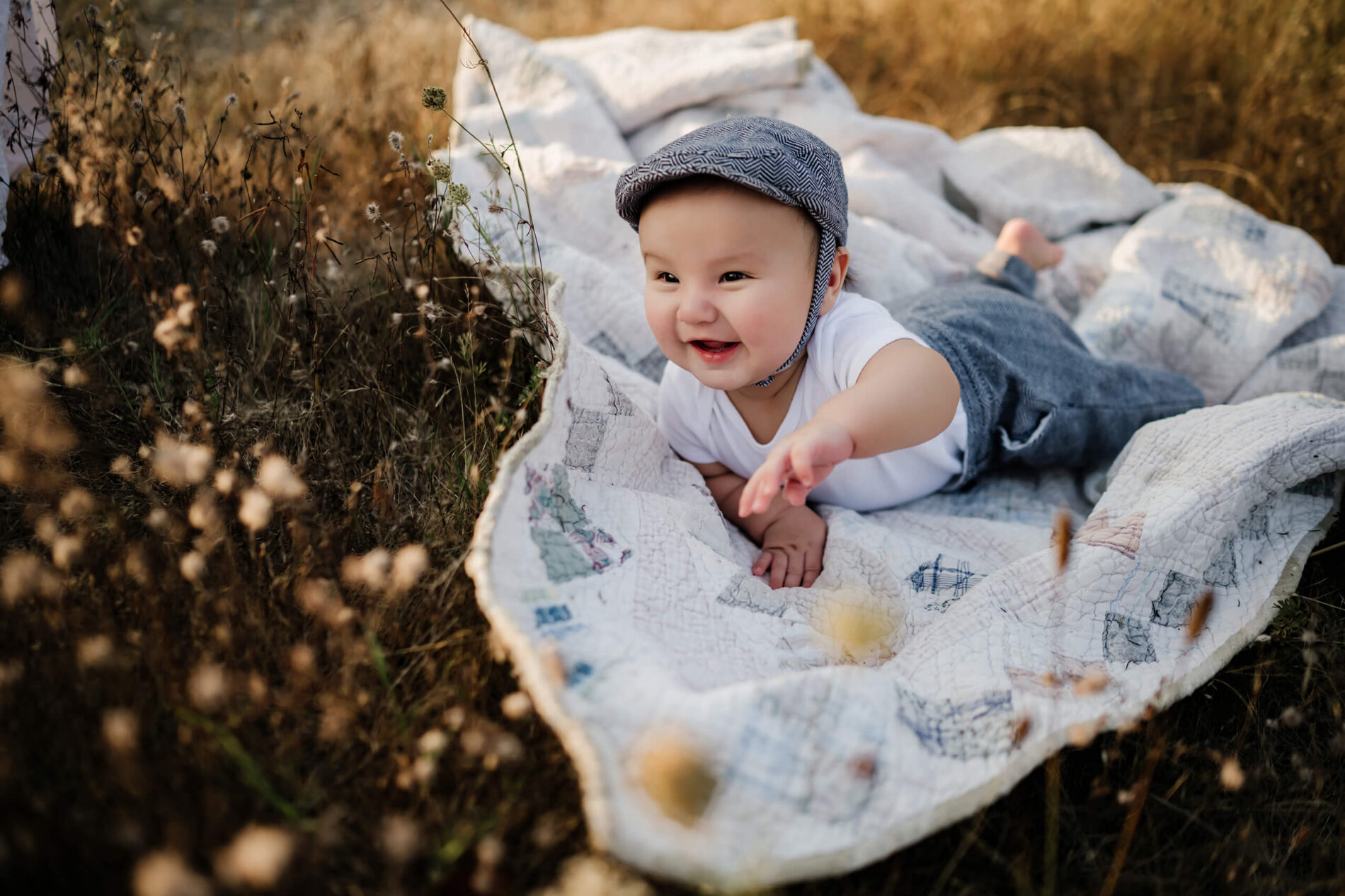 A lifestyle photo of a happy toddler lying on blanket in a field during a family photo shoot near Seattle