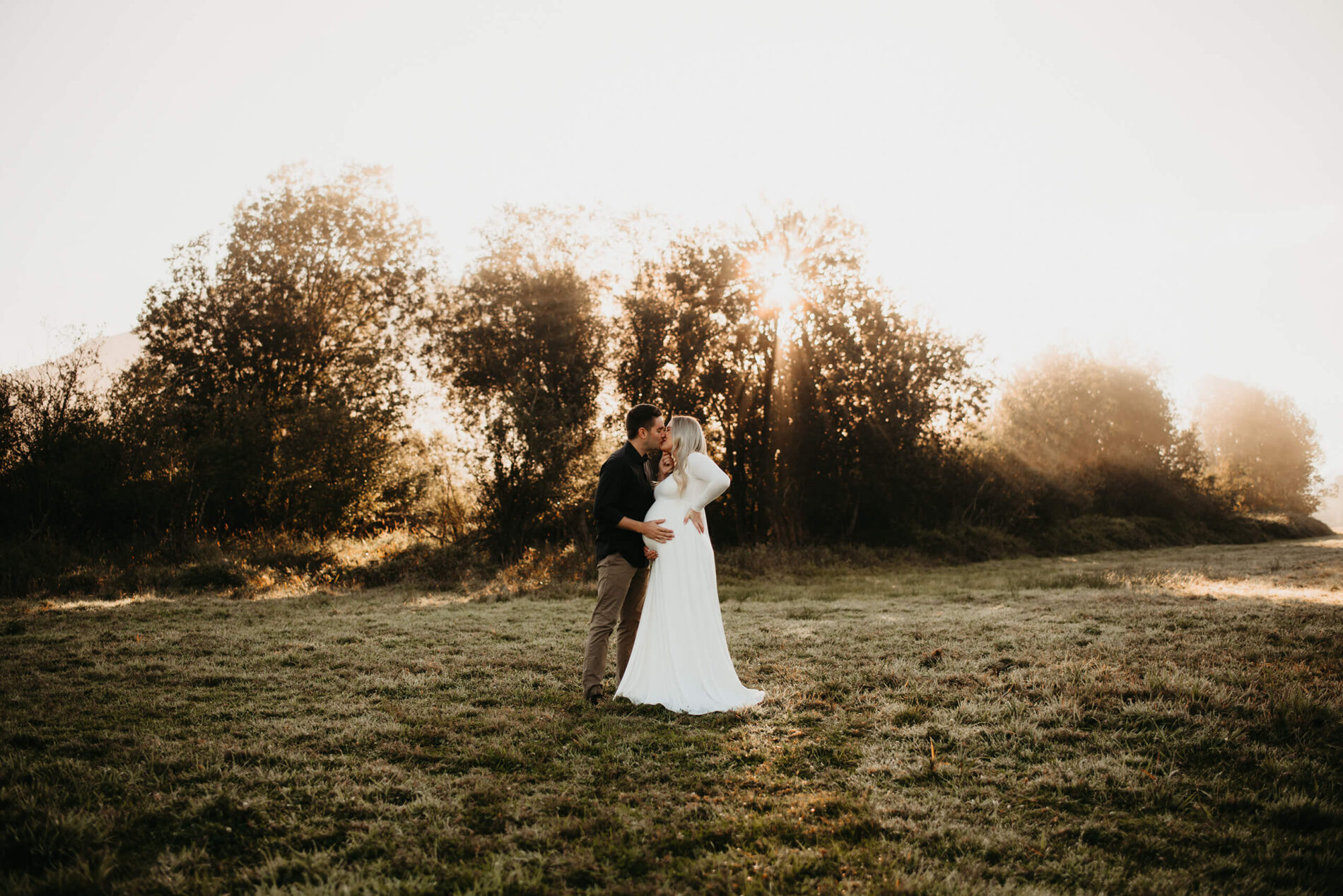 A couple in an open field during sunrise maternity photo session in Seattle area