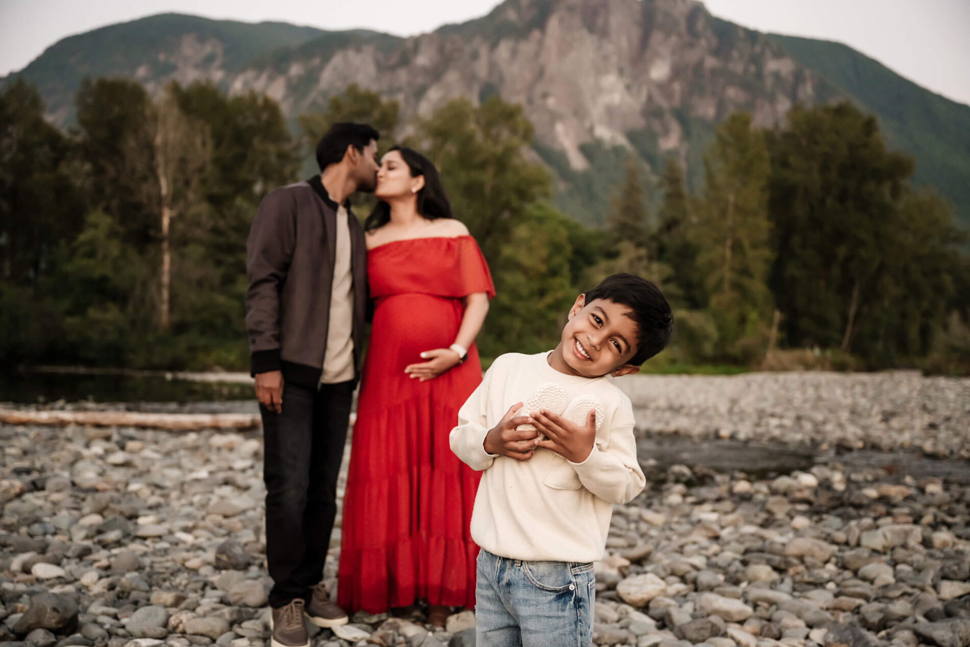 Posing idea for a maternity photoshoot with an older sibling, beautiful mountain views in the background
