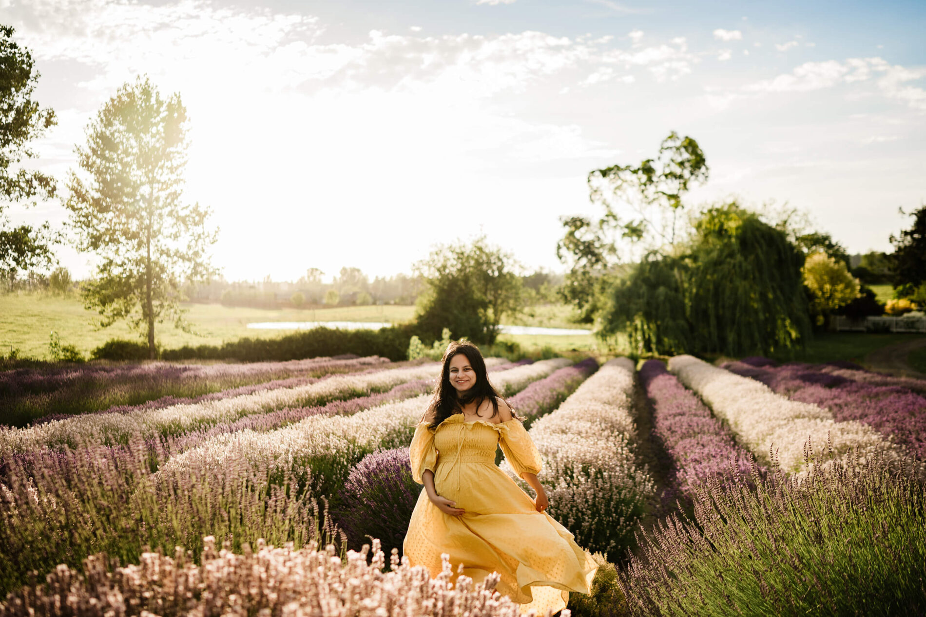A pregnant woman in a yellow maternal dress in a lavender field during a pregnancy photoshoot in Sequim WA