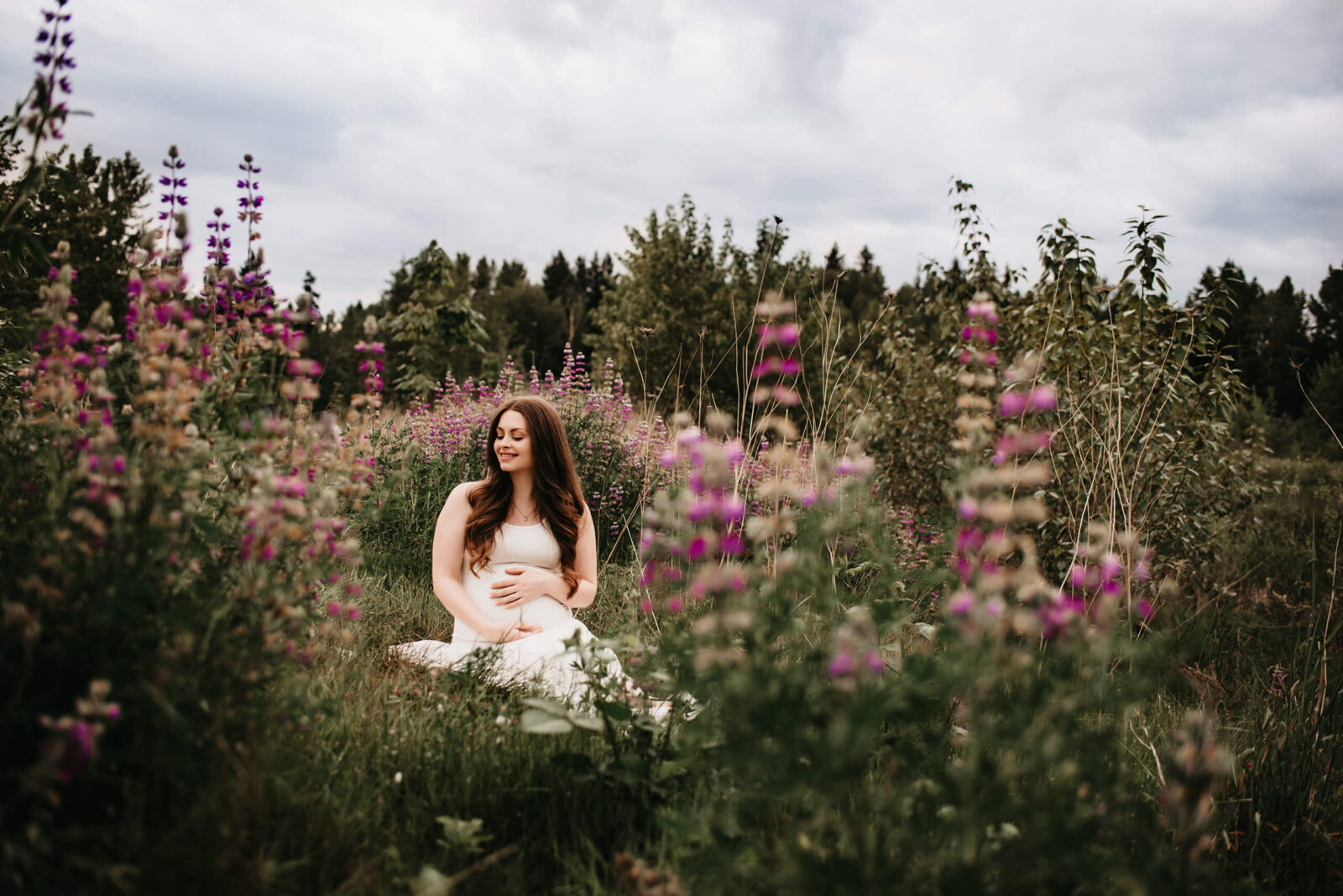 Smiling pregnant woman in a field of lupines during maternity photoshoot in Redmond, WA
