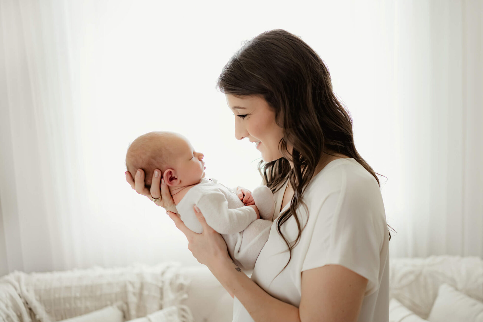 Smiling mom holding her sleeping son on her chest during a newborn photo session in Seattle area studio
