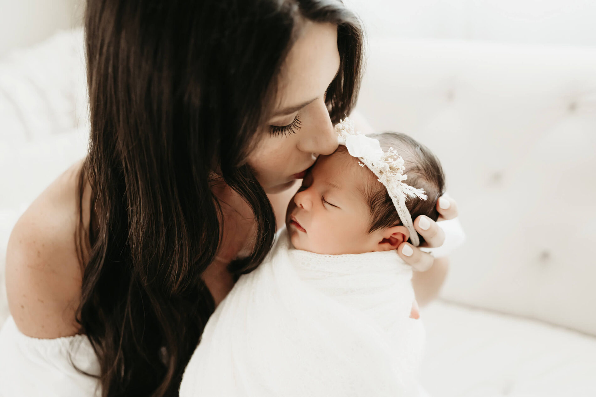 Newborn pose of mom with baby. Mom kissing her baby daughter on the head during a newborn photoshoot in Seattle