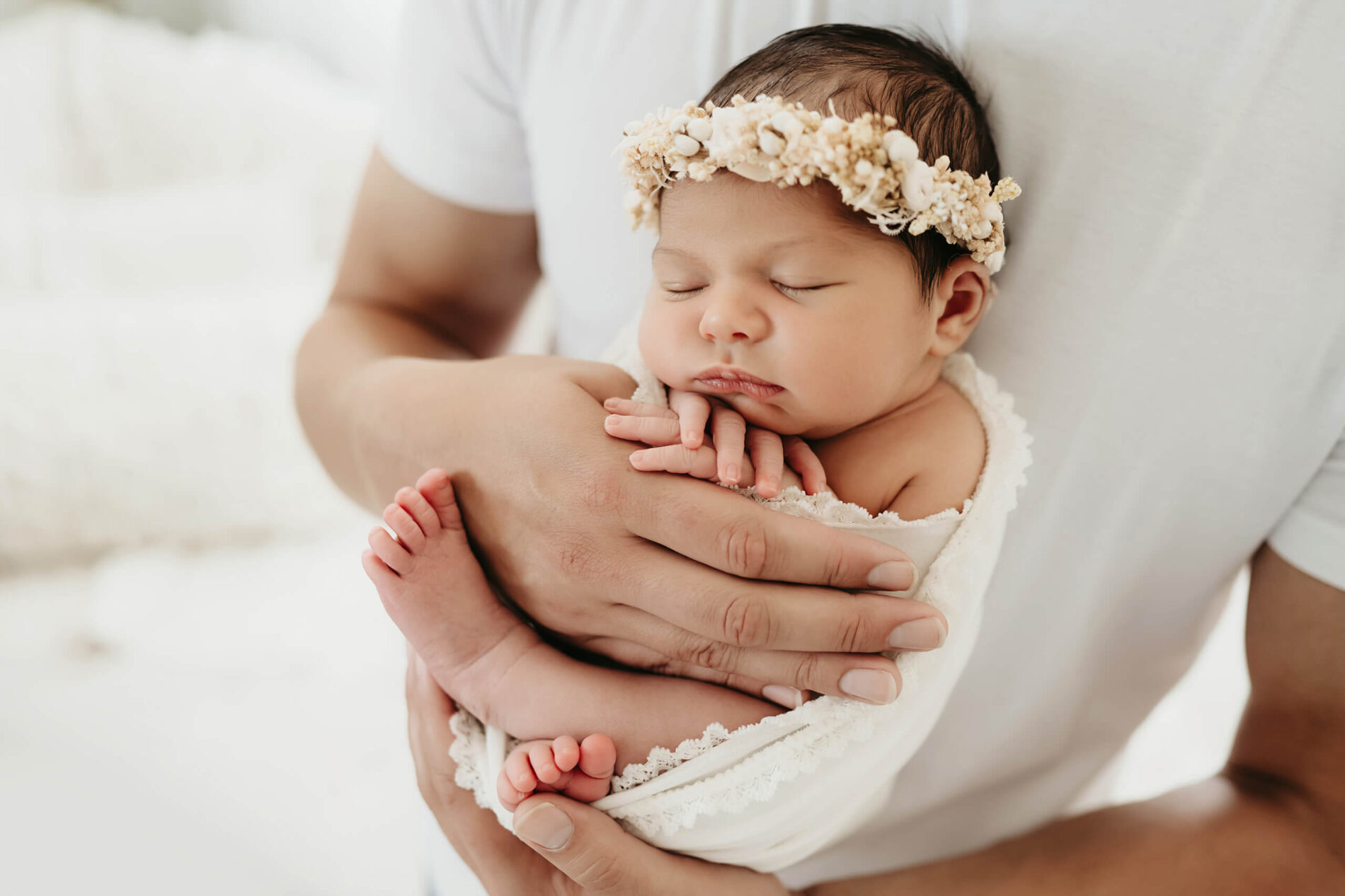 Timeless newborn photo of baby girl with her dad. A father holding his baby daughter on his chest.