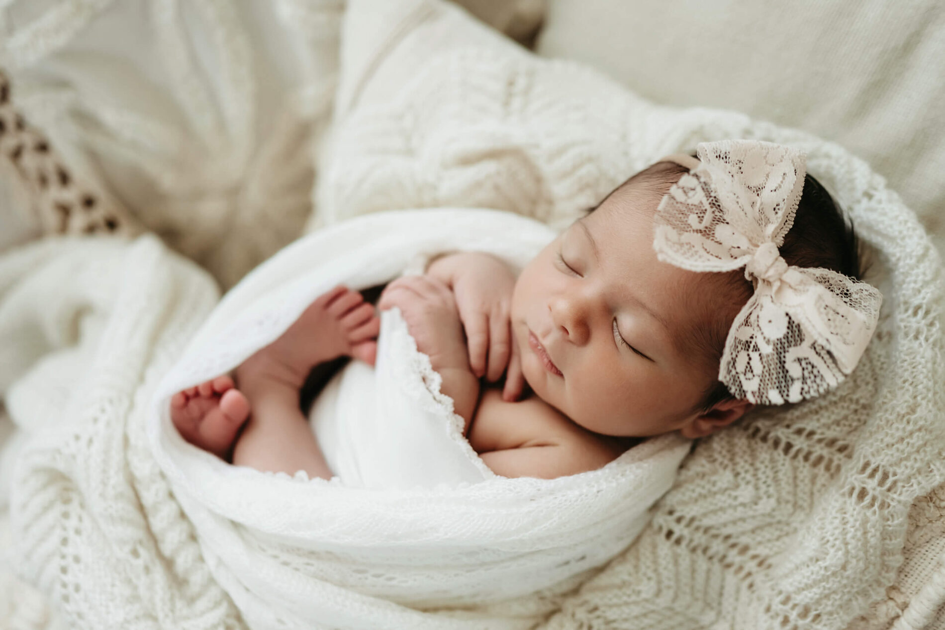 Seattle studio newborn photography with props. Timeless portrait of baby girl cozily wrapped in white blanket and wearing white headband.