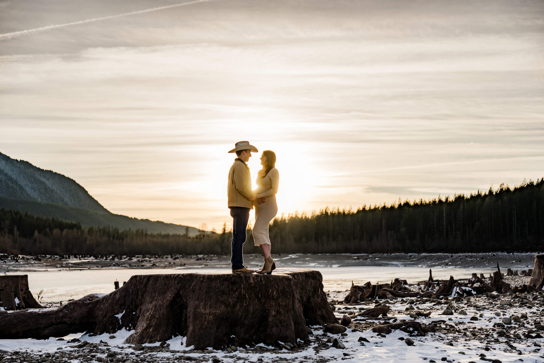 A gorgeous silhouette maternity photo of a couple during sunset with frozen lake and mountains in the background