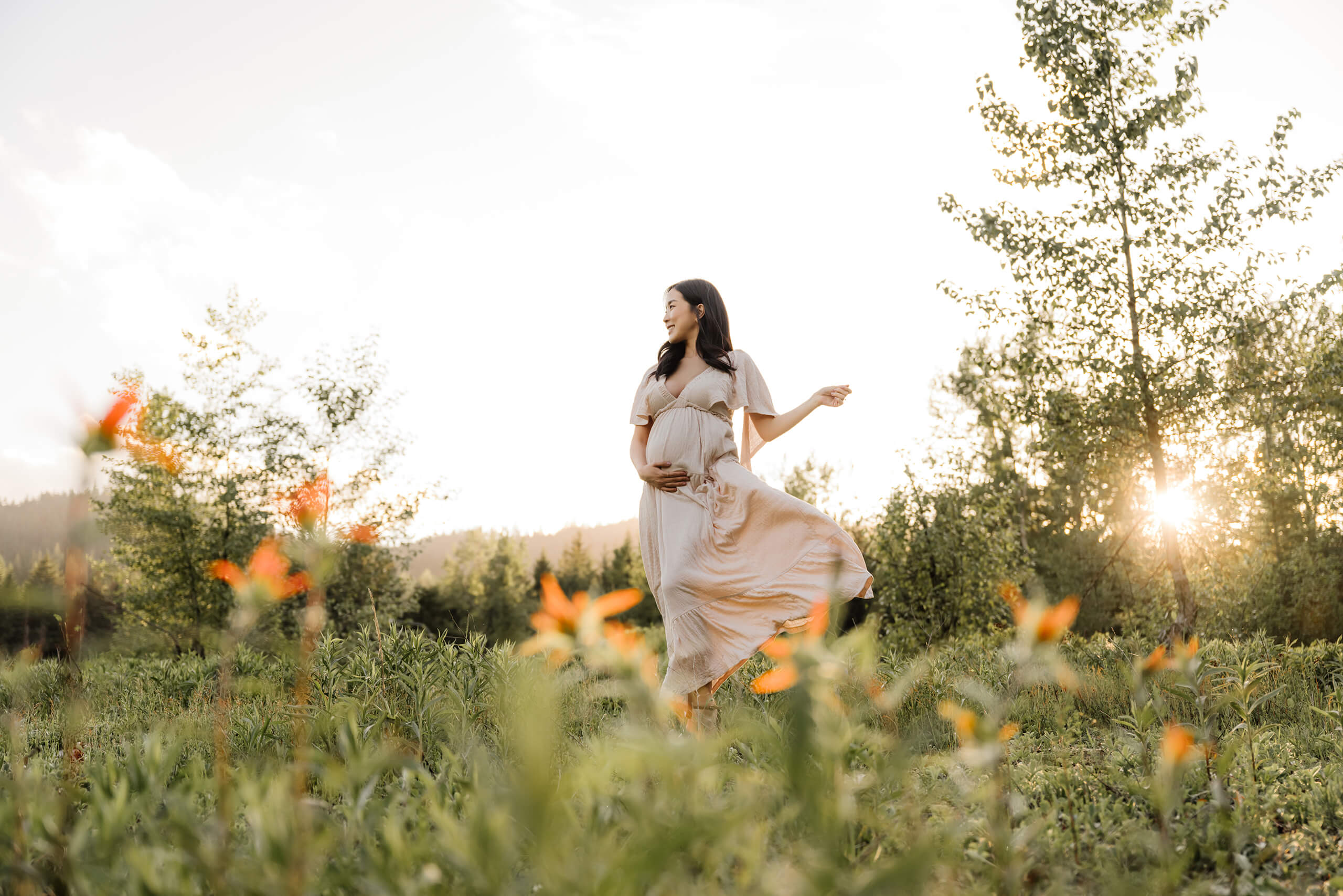 A happy pregnant woman being photographed by Bellevue maternity photographer in a field