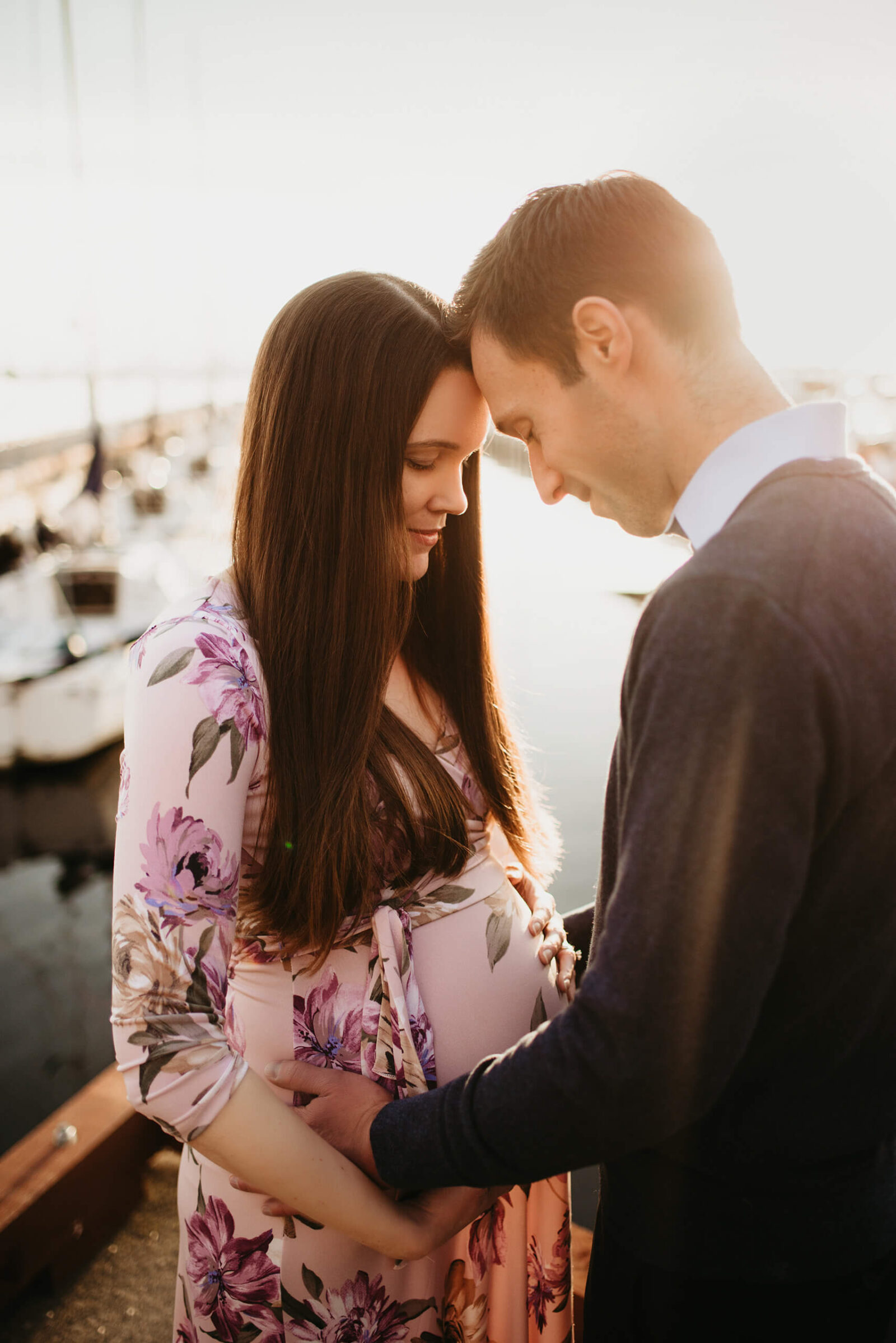 Expecting couple sharing a quiet moment by the waterfront during an outdoor maternity session