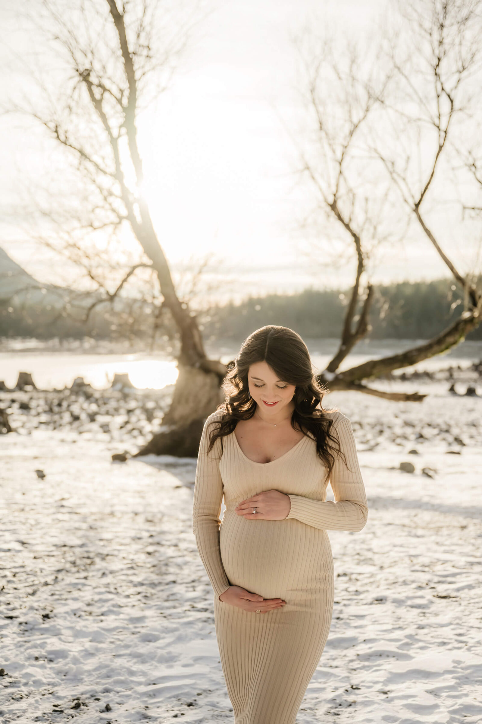 Expecting mother standing in the snow during a winter maternity session