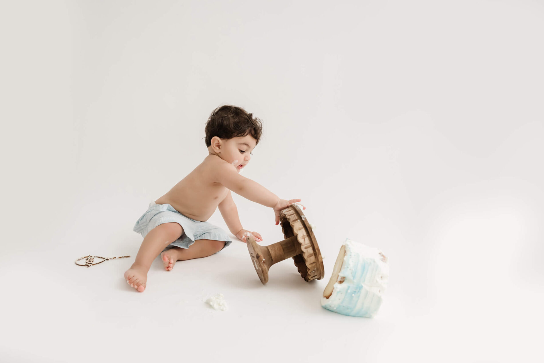 A boy during 1st birthday cake smash photoshoot in a studio in Bellevue WA