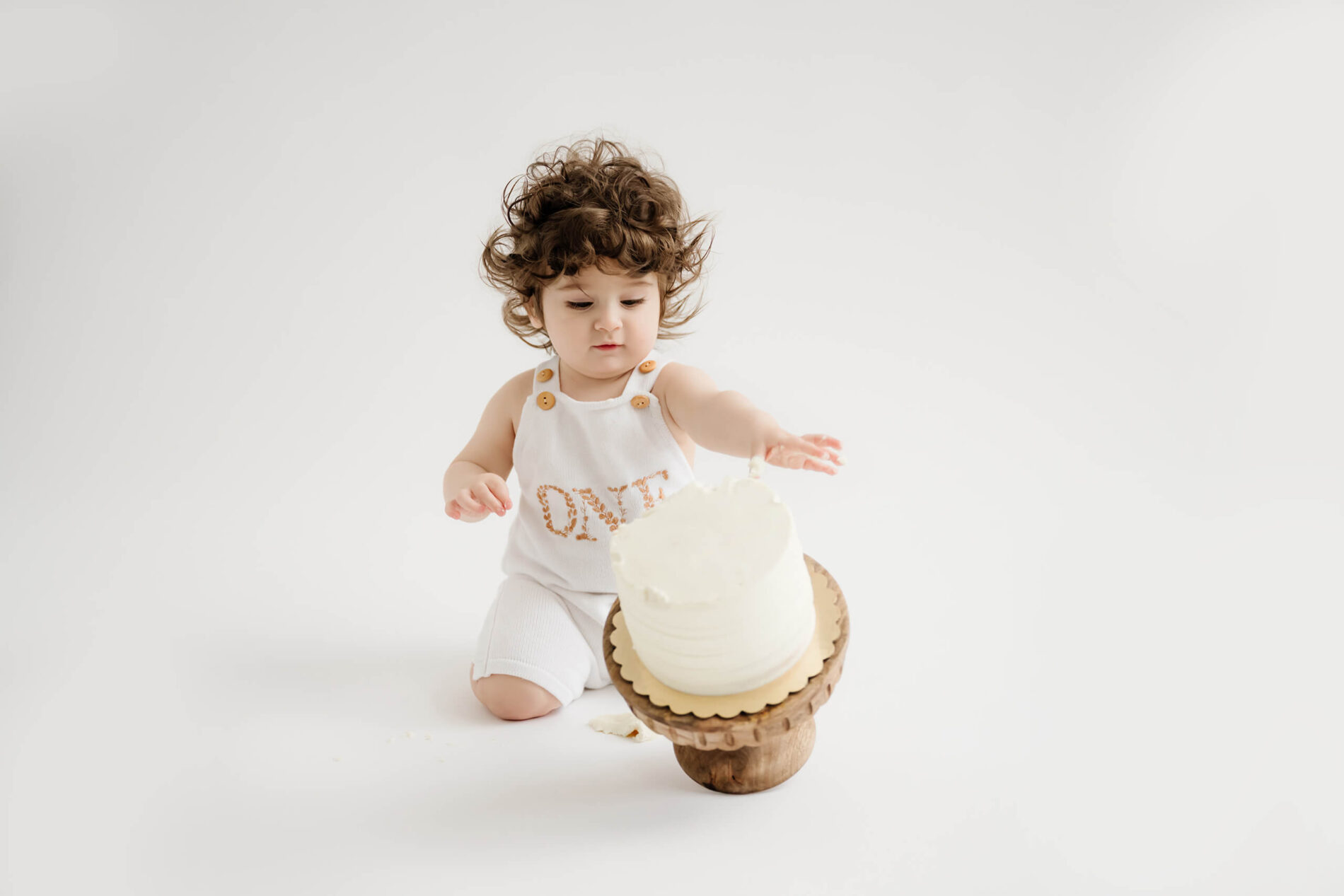 A one year old boy smashing cake during cake smash photoshoot