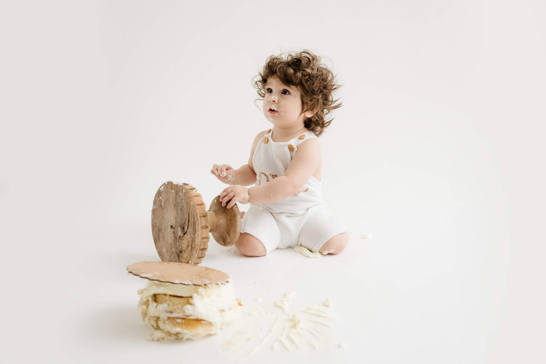 A one year old boy eating cake during cake smash photoshoot