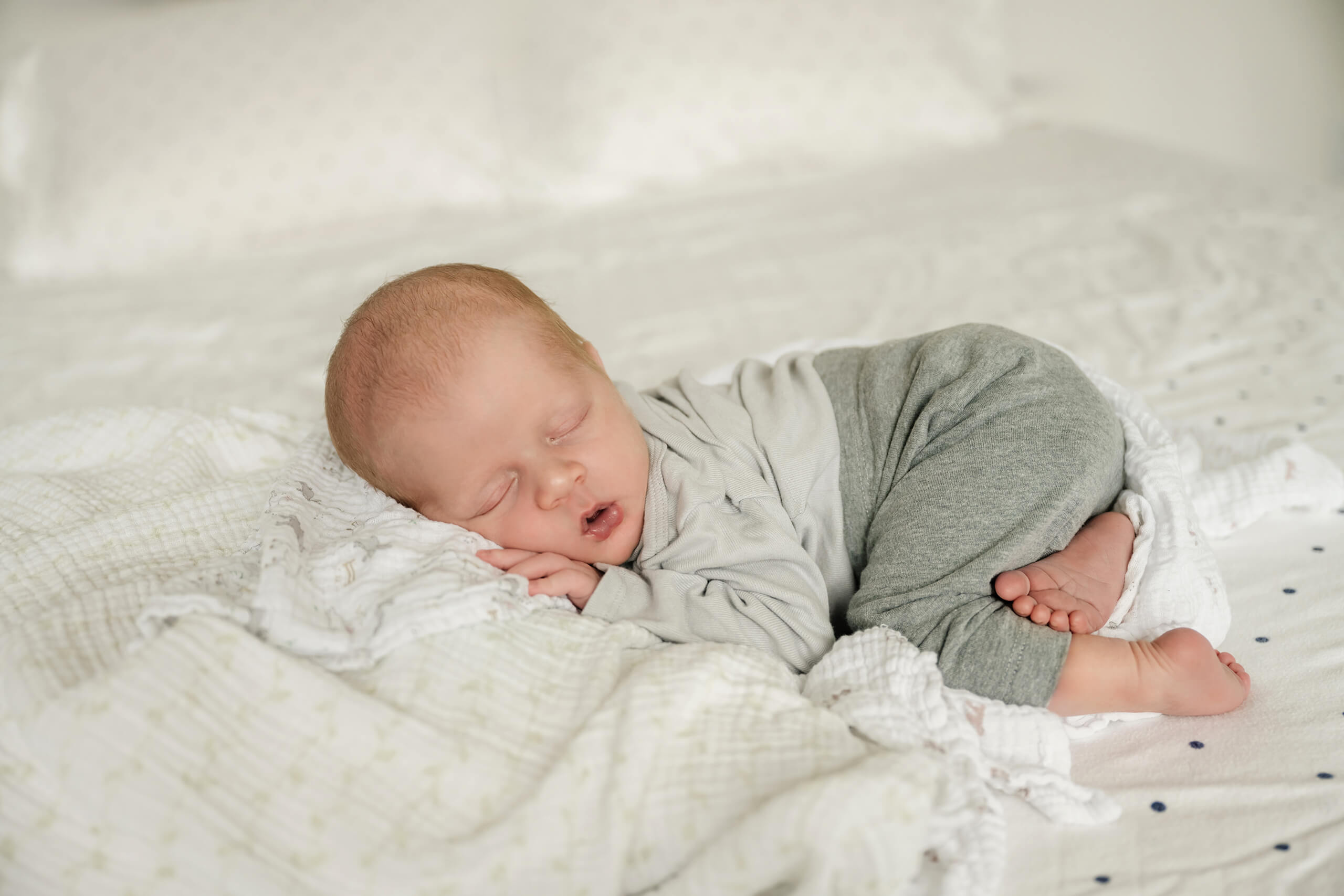 Natural portrait of a newborn posed on parent's bed during in-home photoshoot.
