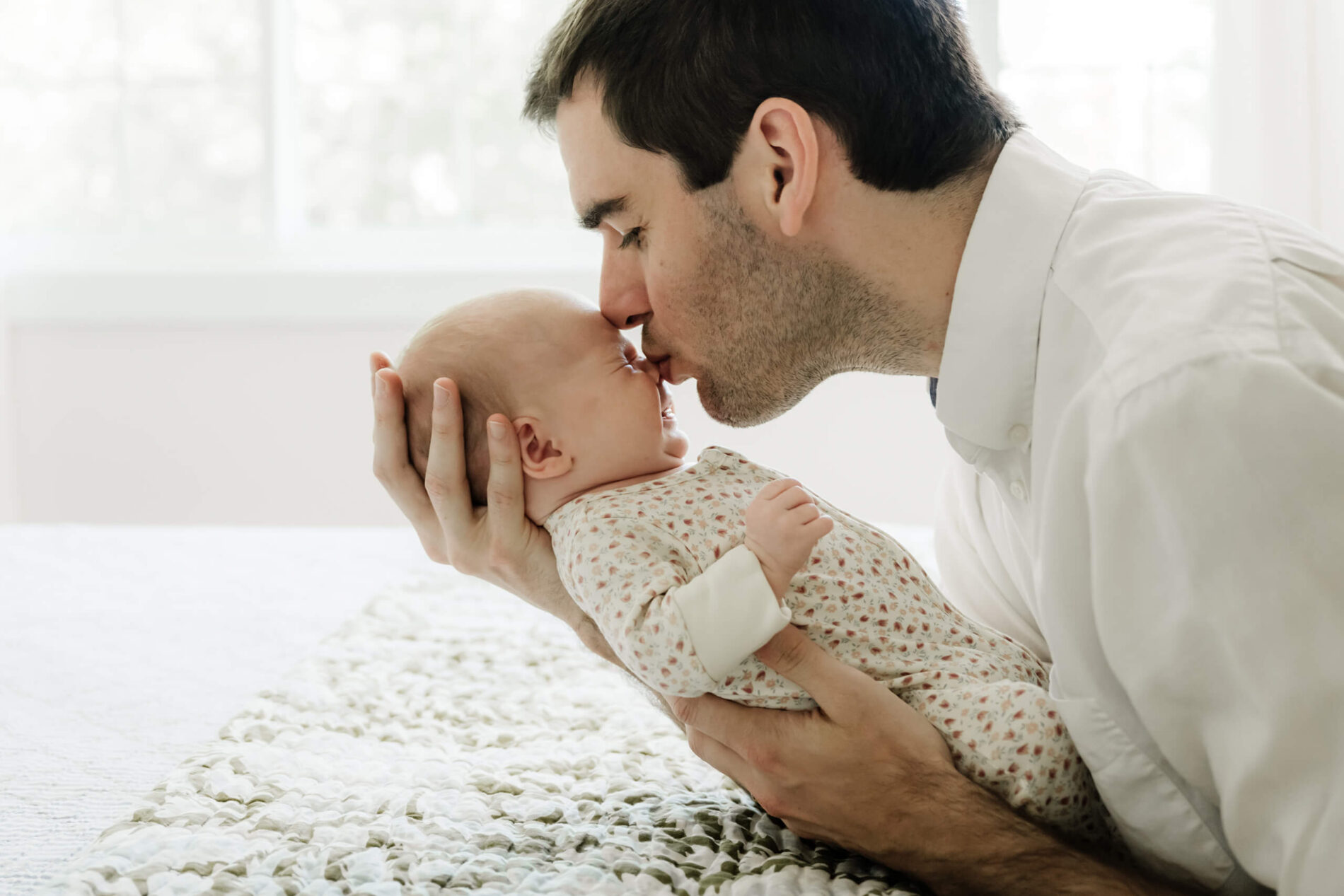 Portrait of dad kissing his son taken during in-home newborn session