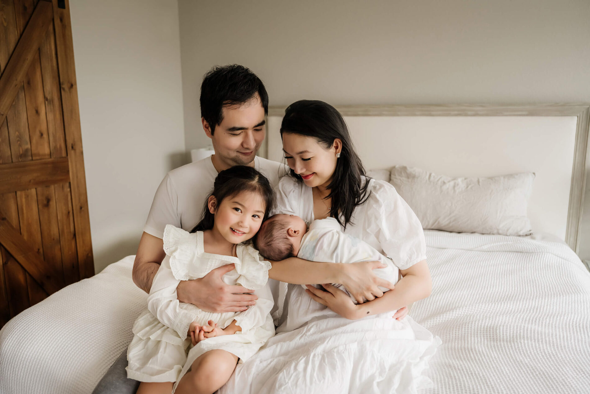 Family portrait with a newborn taken in a bedroom during newborn in-home session
