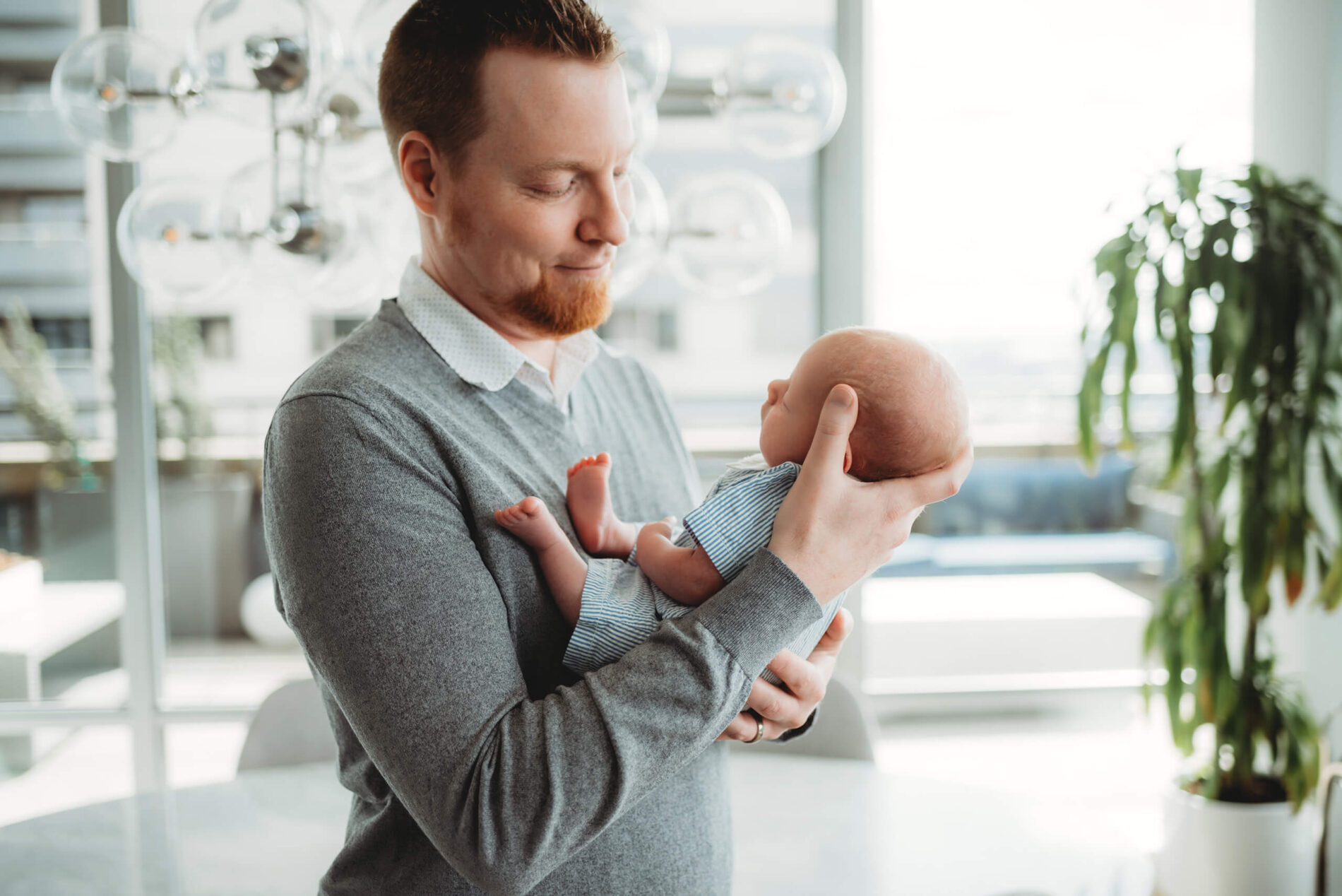 Dad holding sleeping son during in-home newborn photoshoot