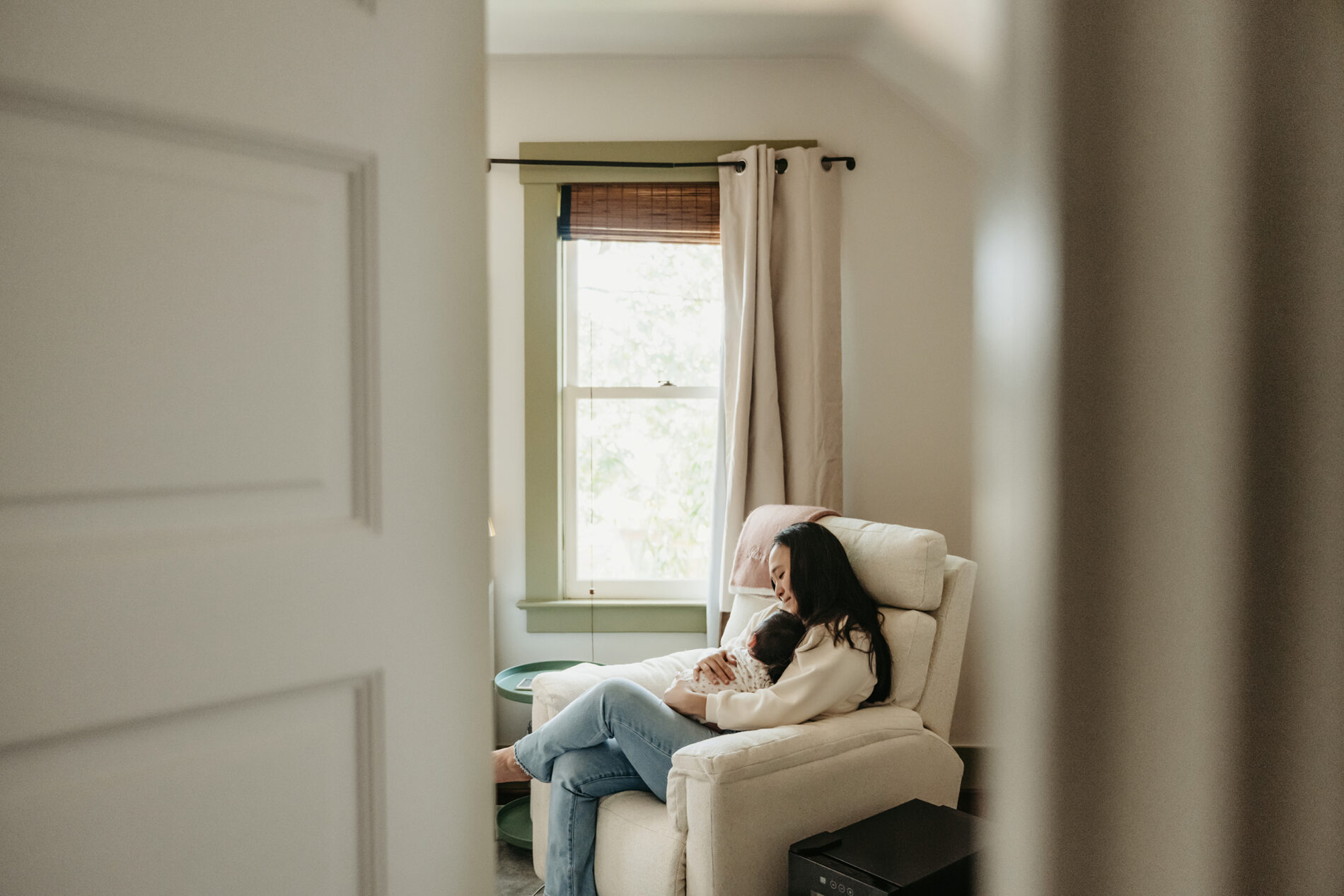 Cozy lifestyle portrait of mom with son in a nursery taken during newborn in-home session